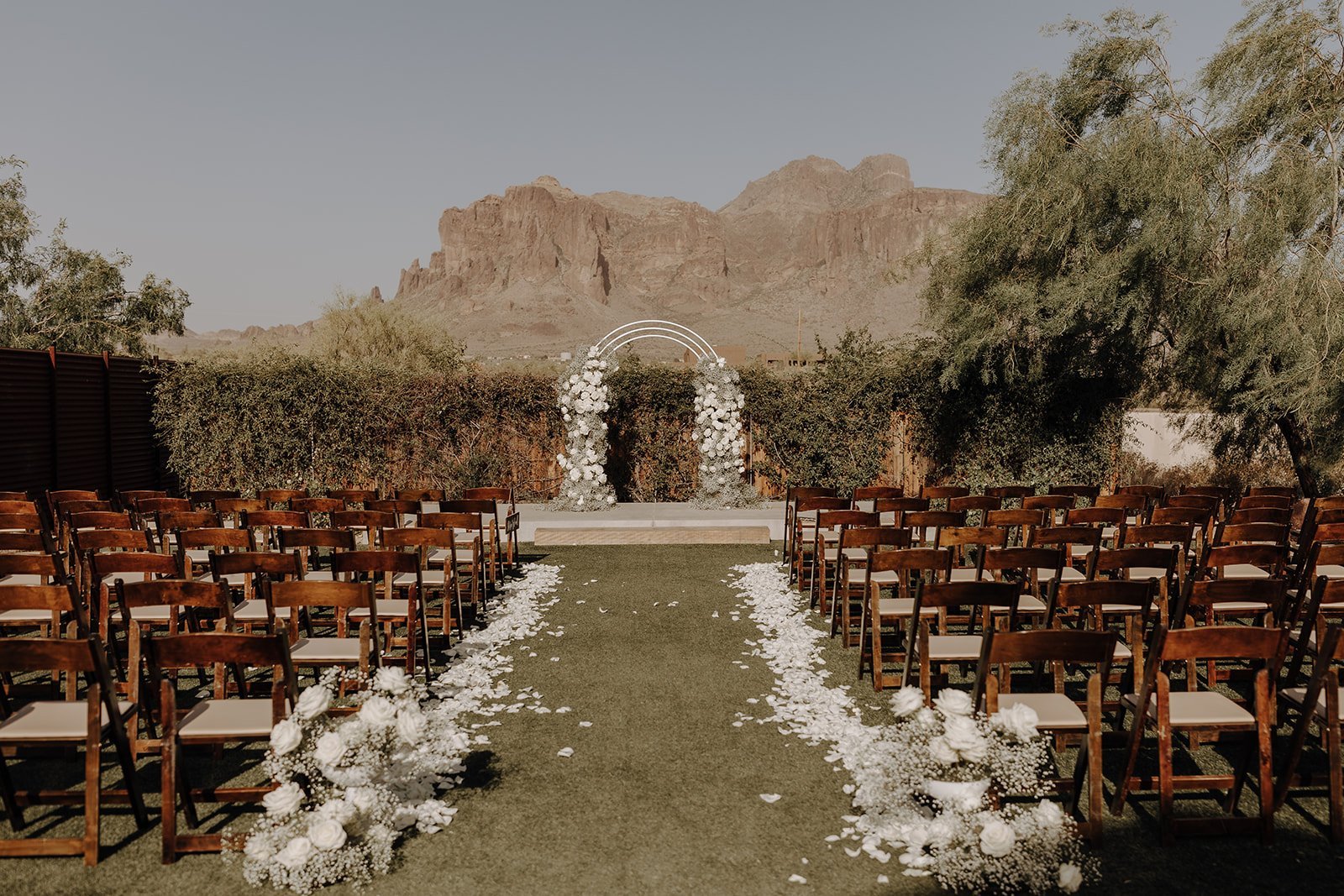 Outdoor desert wedding ceremony setup with white floral arch at The Paseo venue