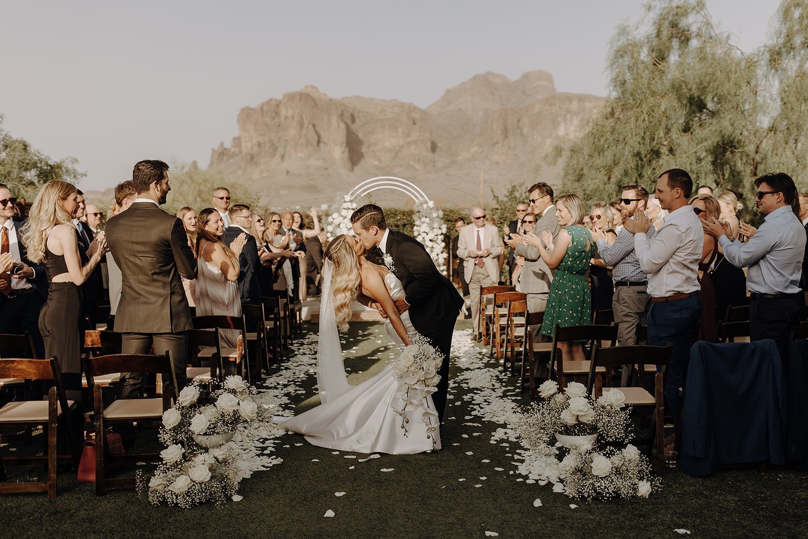 Bride and groom kissing at the end of the wedding aisle for their desert wedding in Arizona