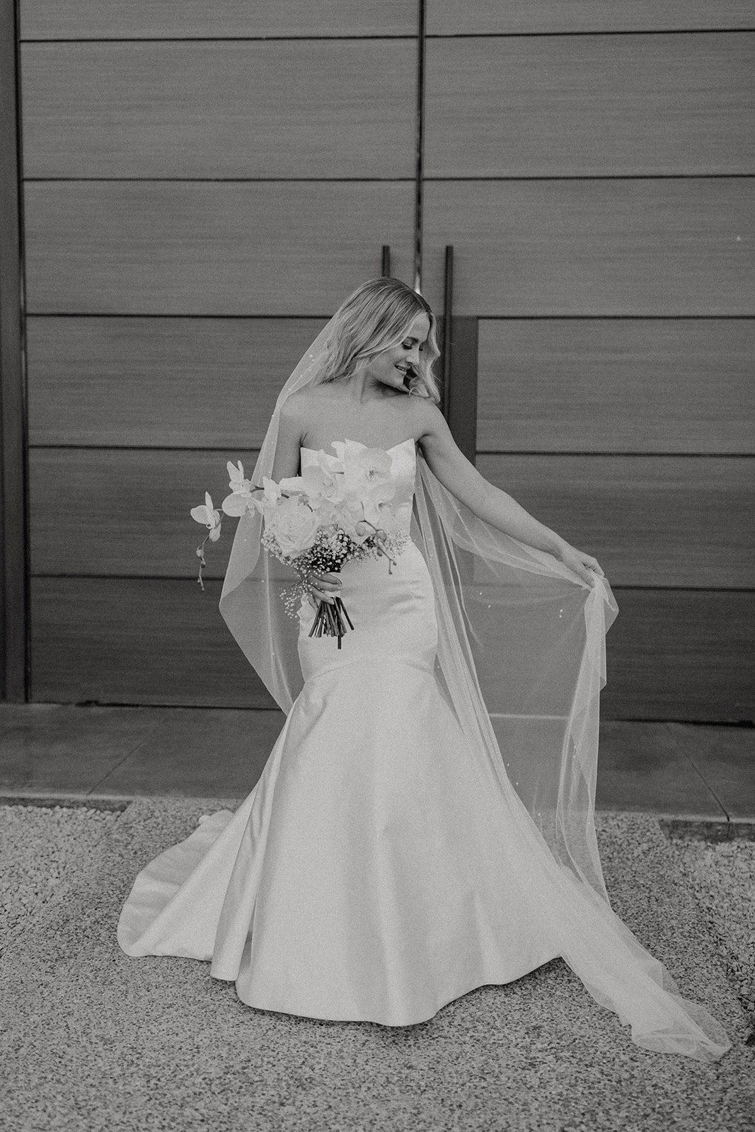 Bride lifting her veil to the side while holding a floral wedding bouquet