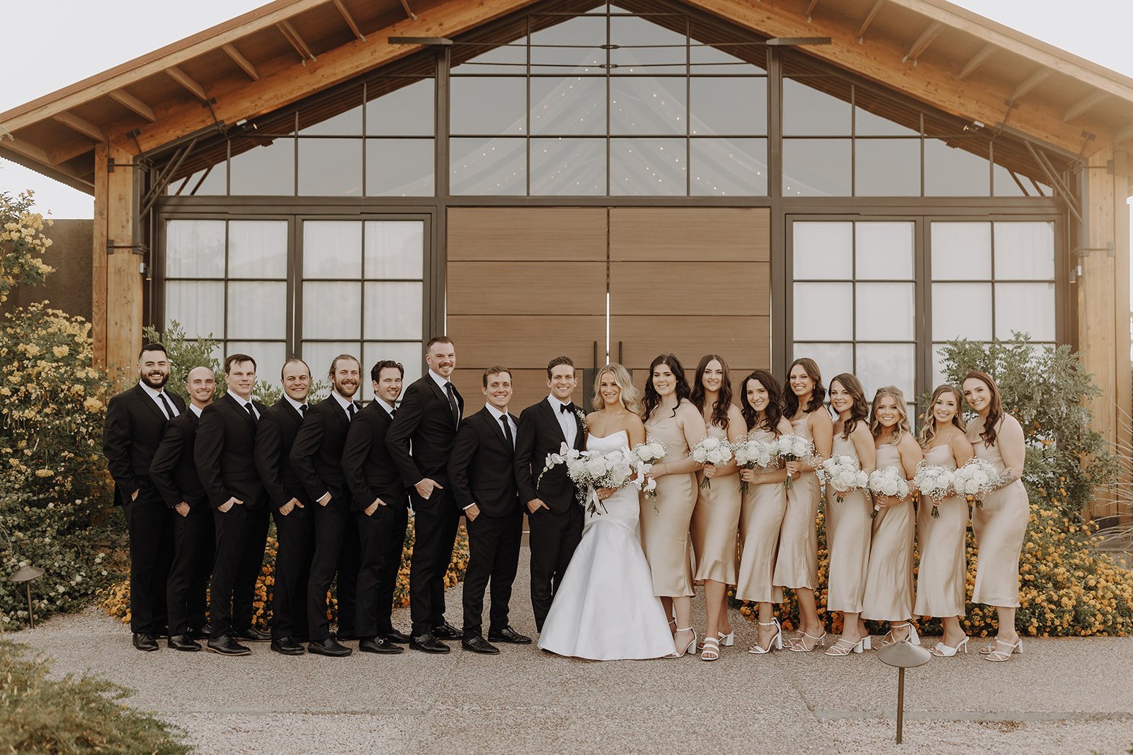 Wedding party in black suits and champagne colored dresses