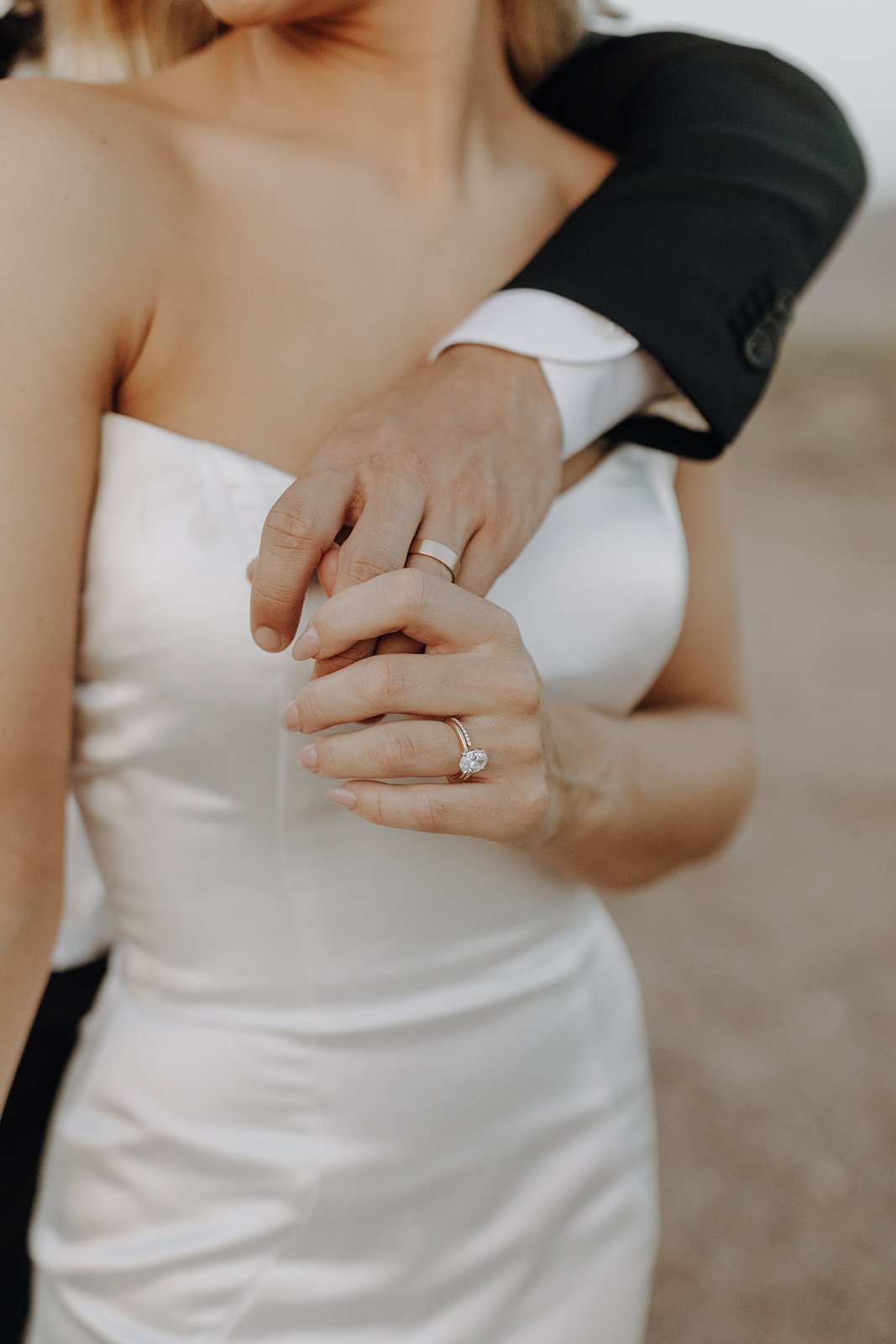 Bride wearing gold and diamond wedding ring and groom wearing gold wedding band during desert wedding portraits