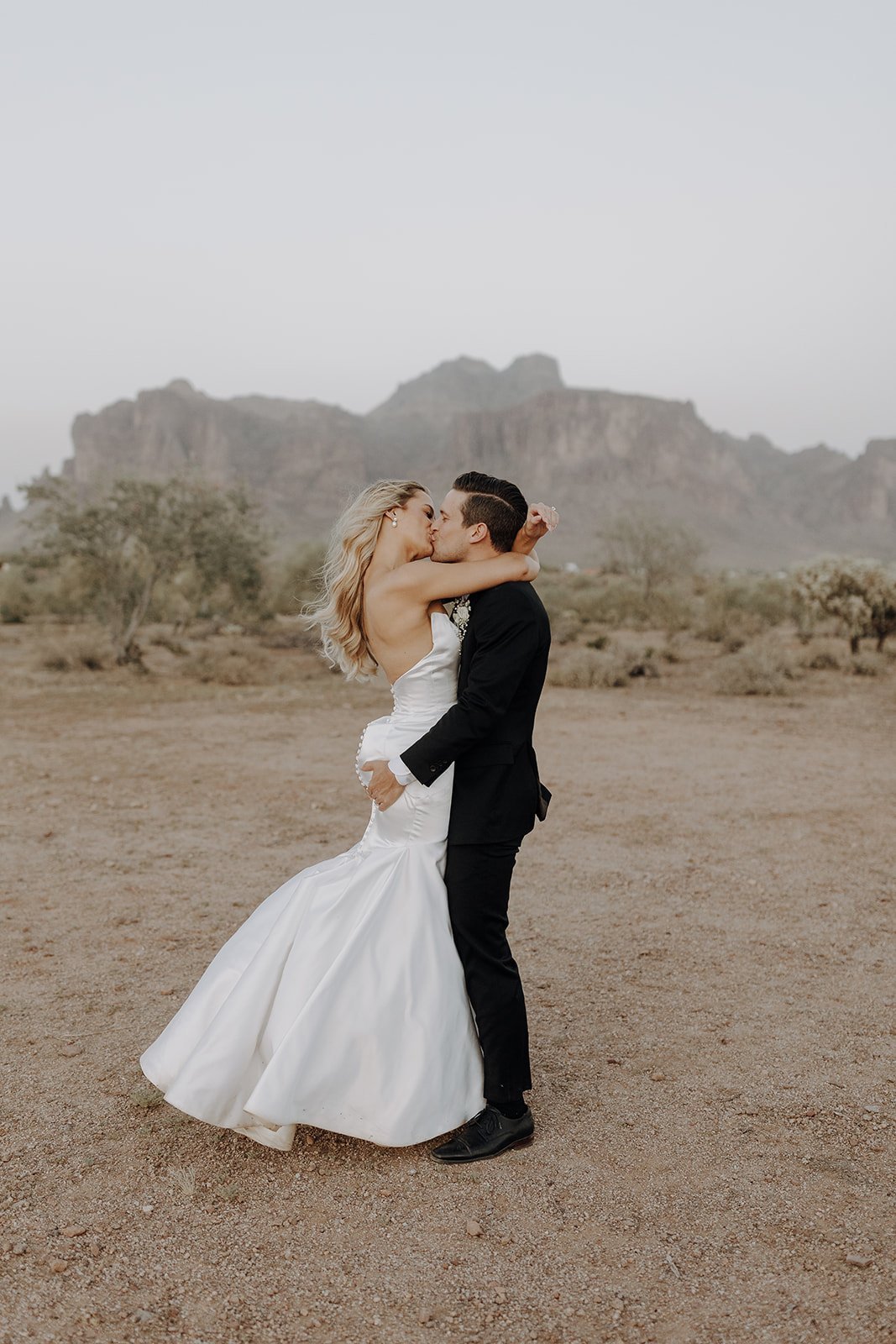 Bride and groom kissing in the desert for their couple photo session