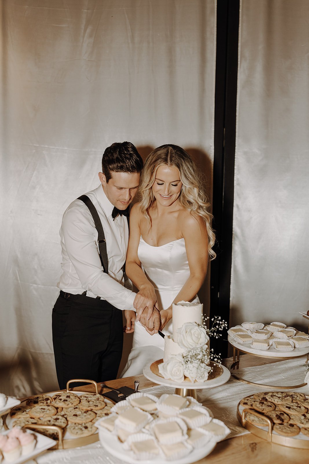 Bride and groom cutting white wedding cake at desert wedding reception