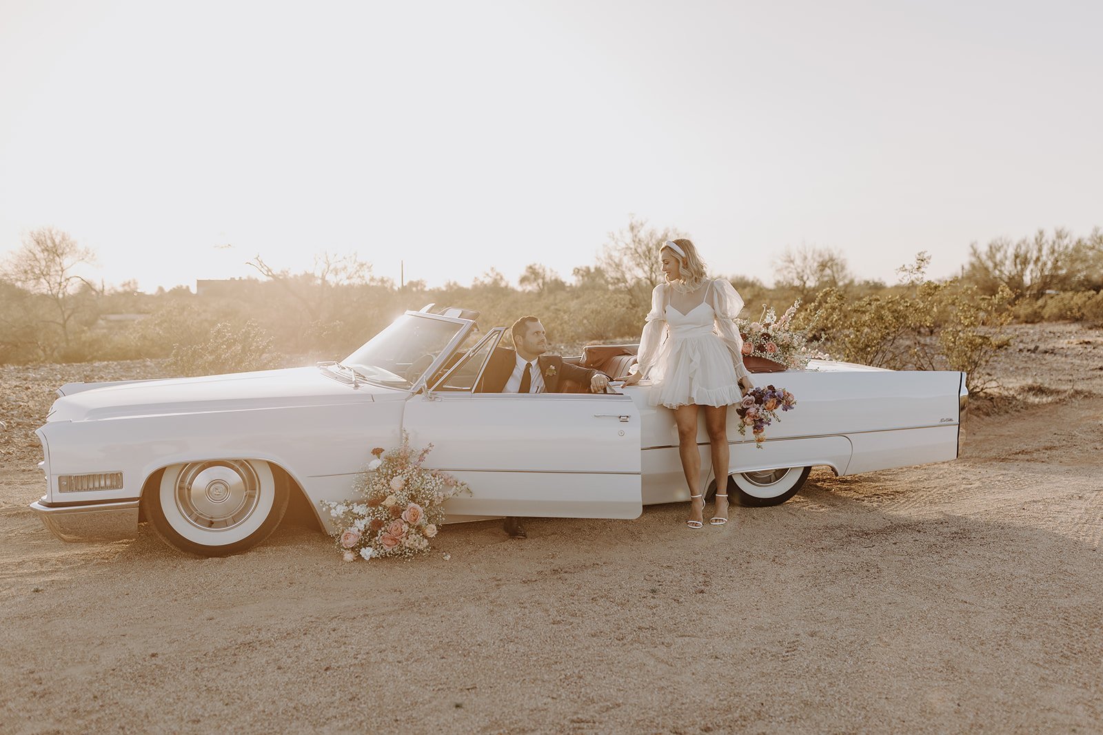 Groom stepping out of vintage white convertible for wedding styled shoot