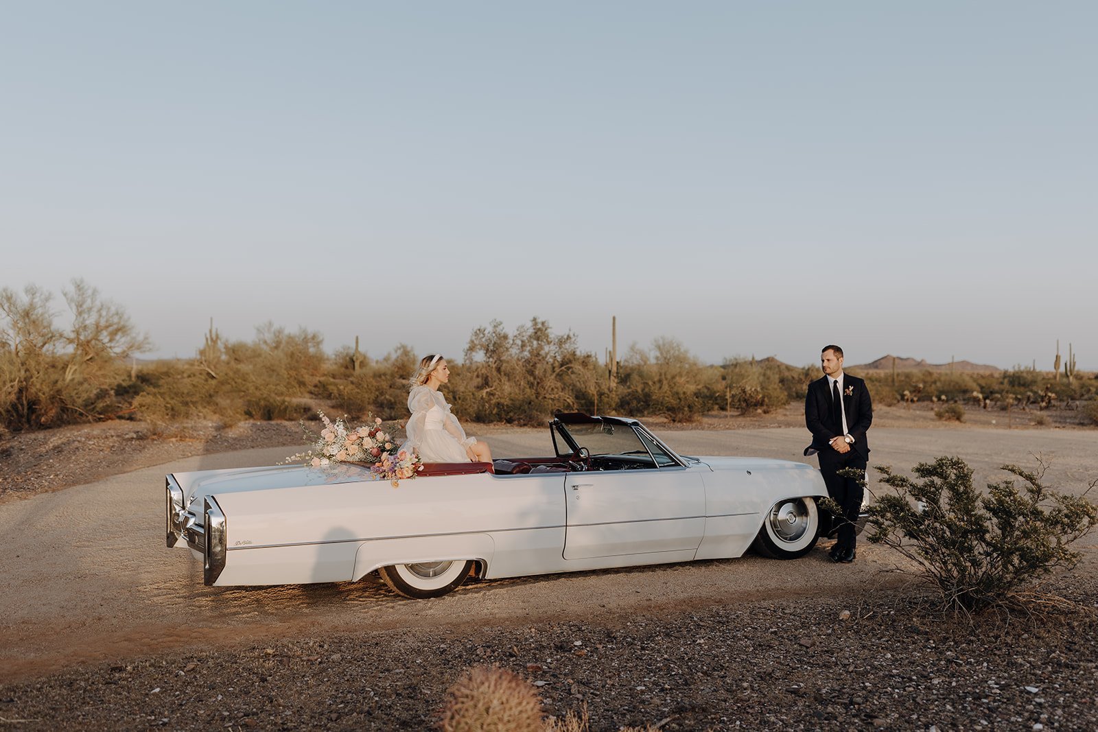 Bride sitting in the back of vintage white convertible