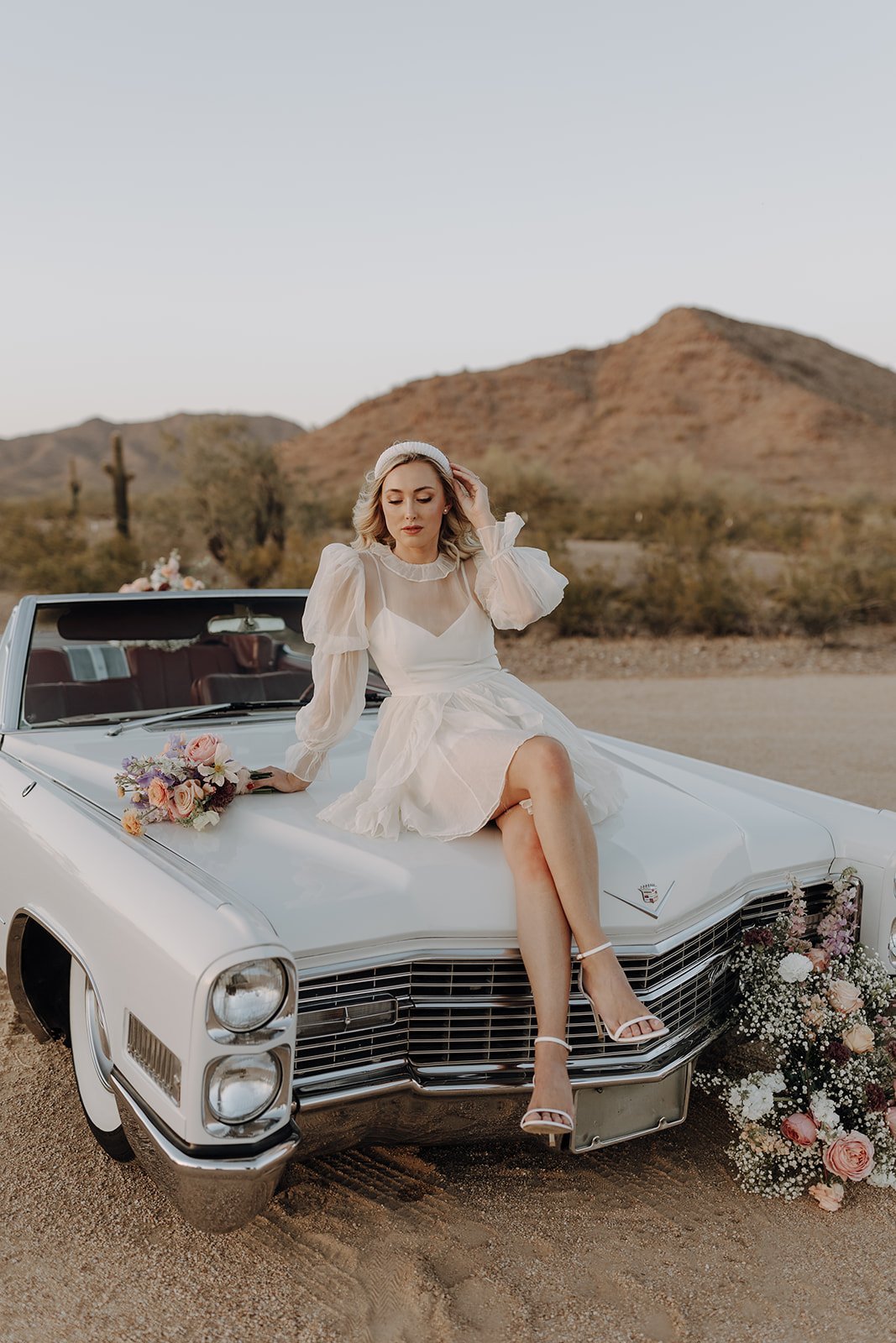 Bride sitting on top of vintage white convertible