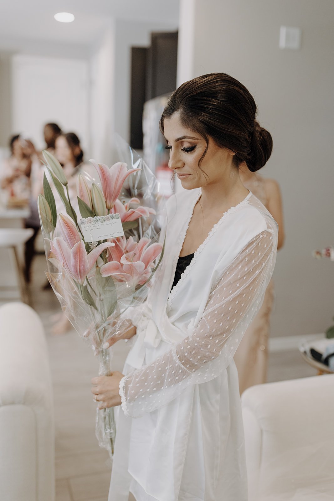 Bride holding pink lilies during getting ready morning 