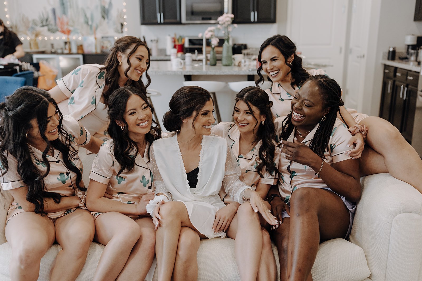 Bride sitting on a couch with wedding party during wedding day morning