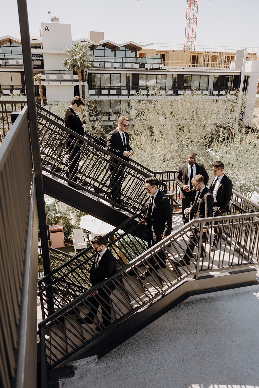 Groomsmen in black suits walking down black iron staircase