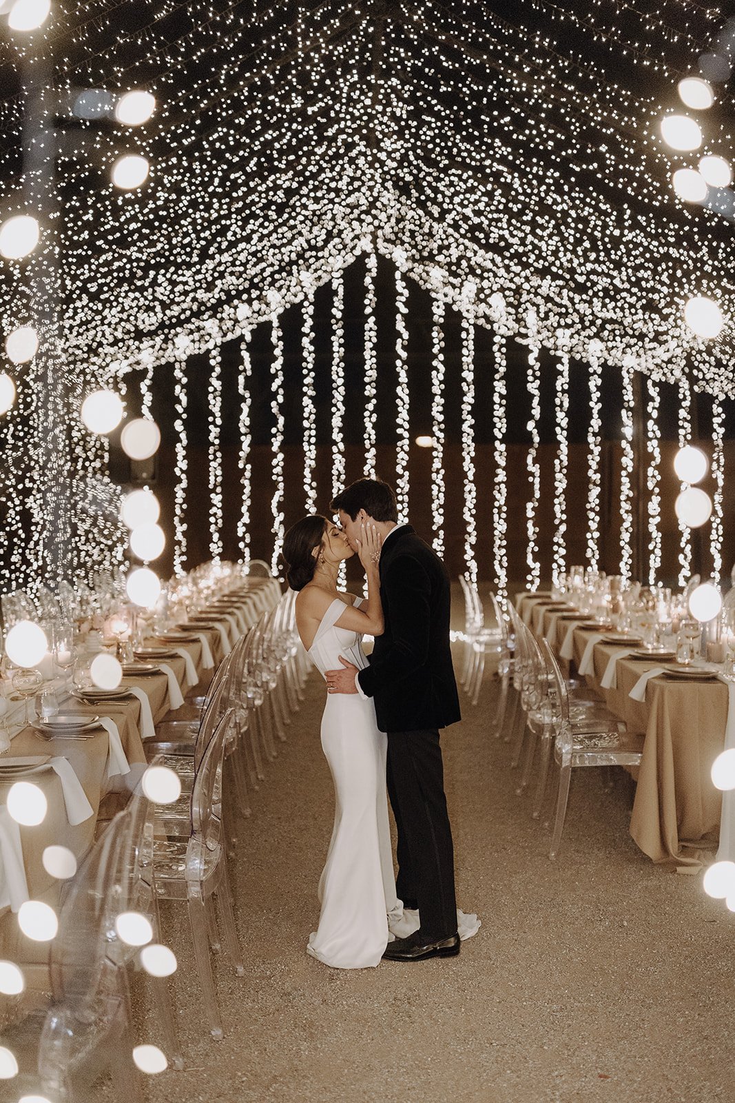 Bride and groom kissing under the twinkle light tent at their Persian wedding reception