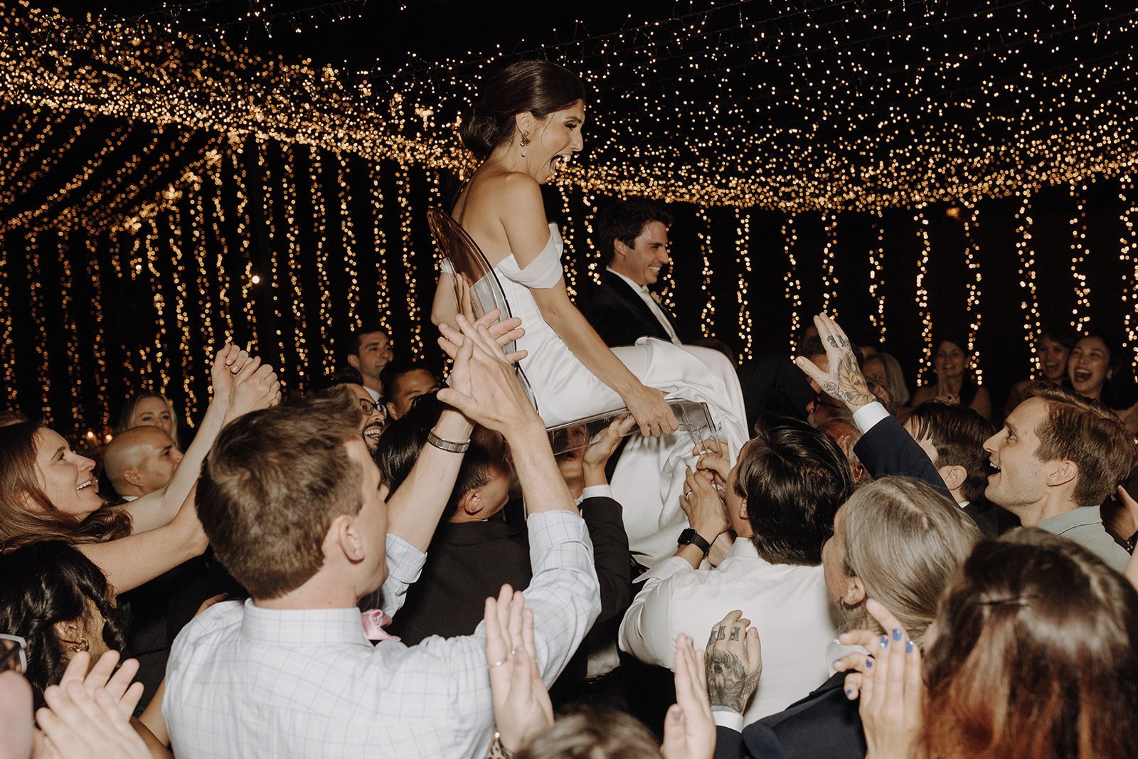 Bride being lifted into the air on an acrylic chair during Persian wedding reception dance floor