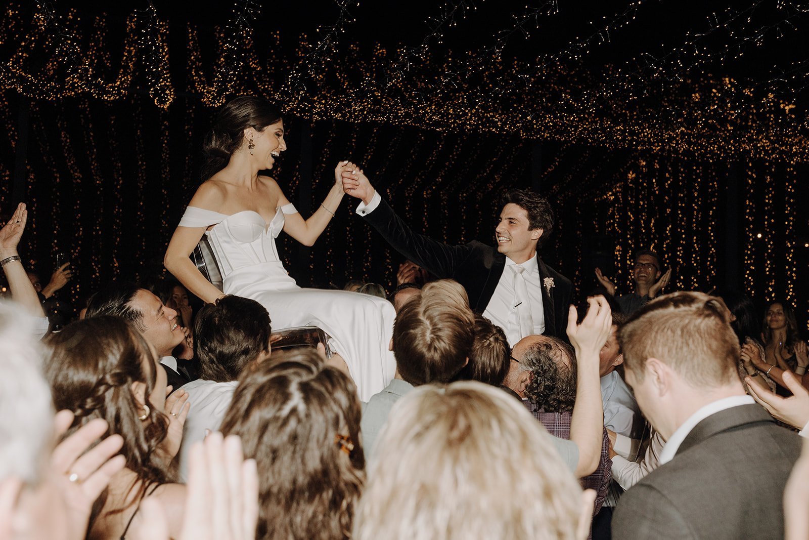 Bride and groom being lifted in the air during wedding reception dancing