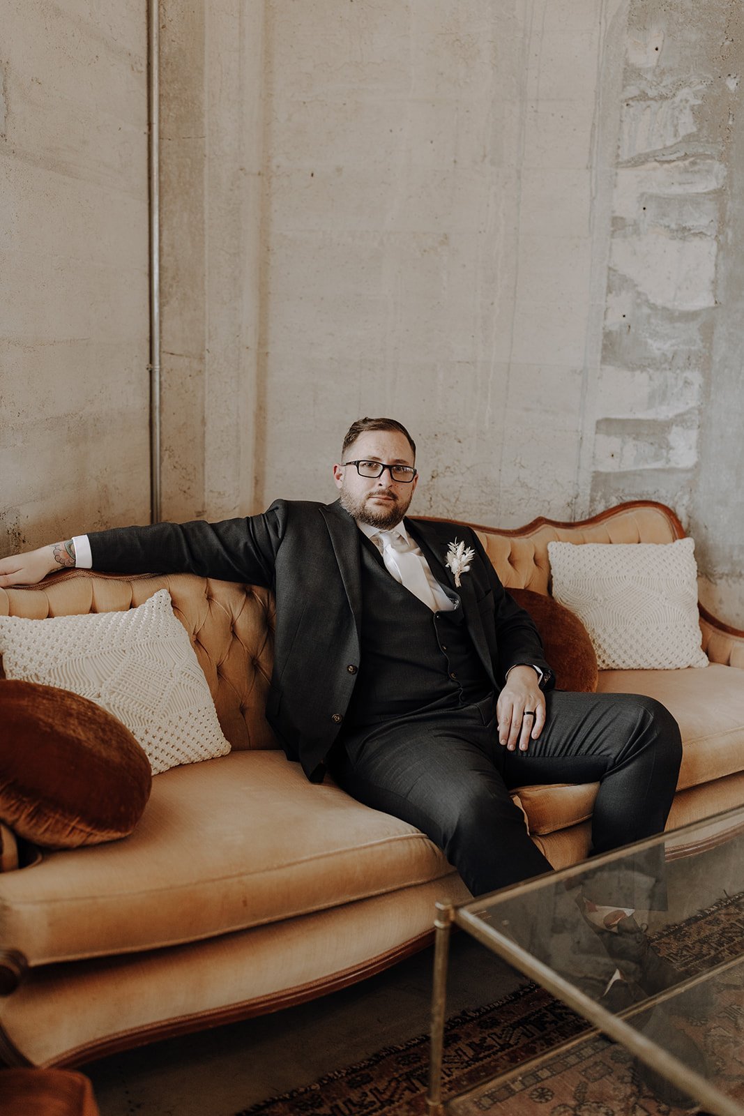 Groom sitting on peach colored couch at the Ice Plant Bldg wedding venue in Austin, Texas