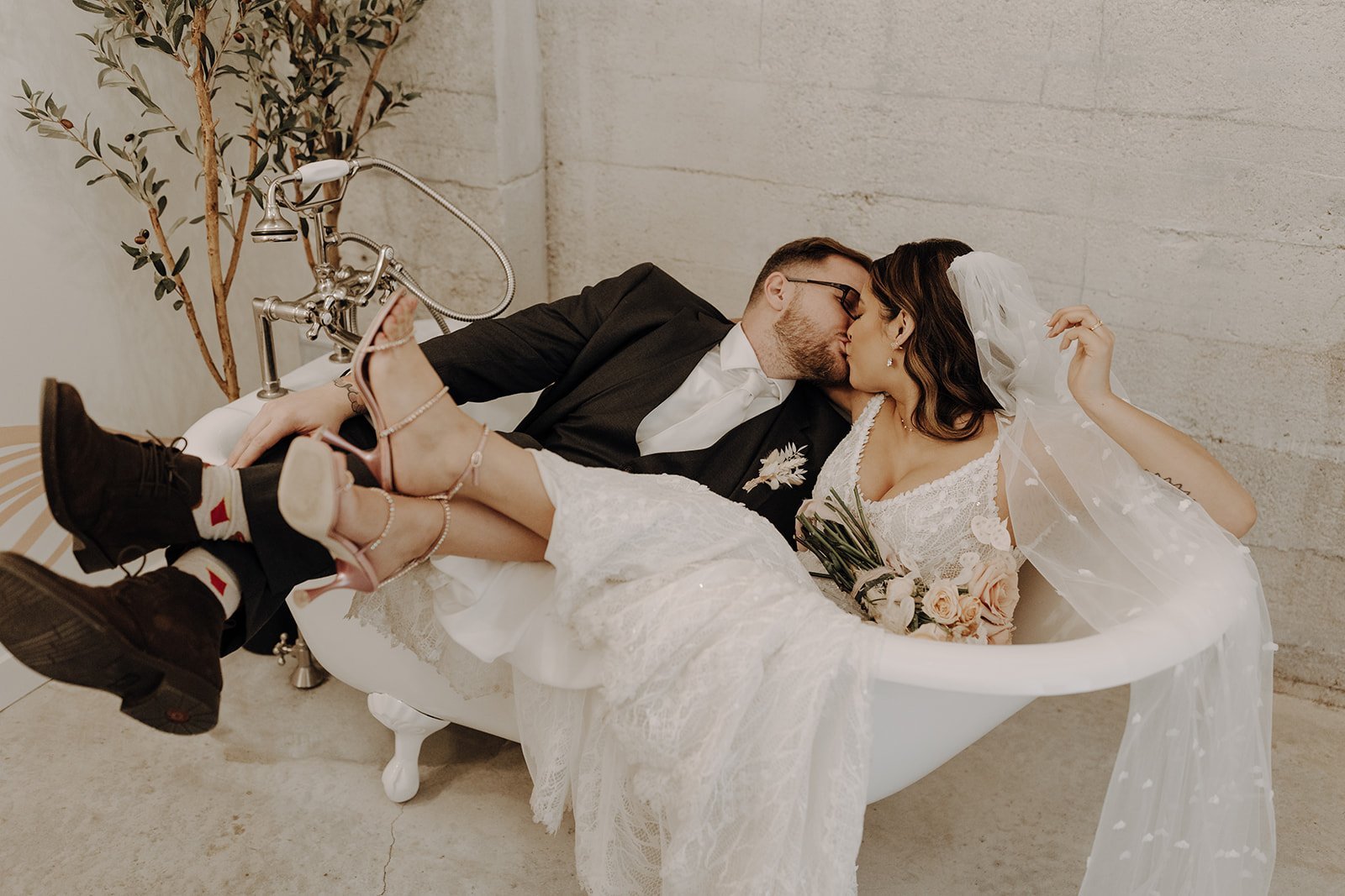 Bride and groom sitting and kissing in a white clawfoot tub at an Austin wedding venue