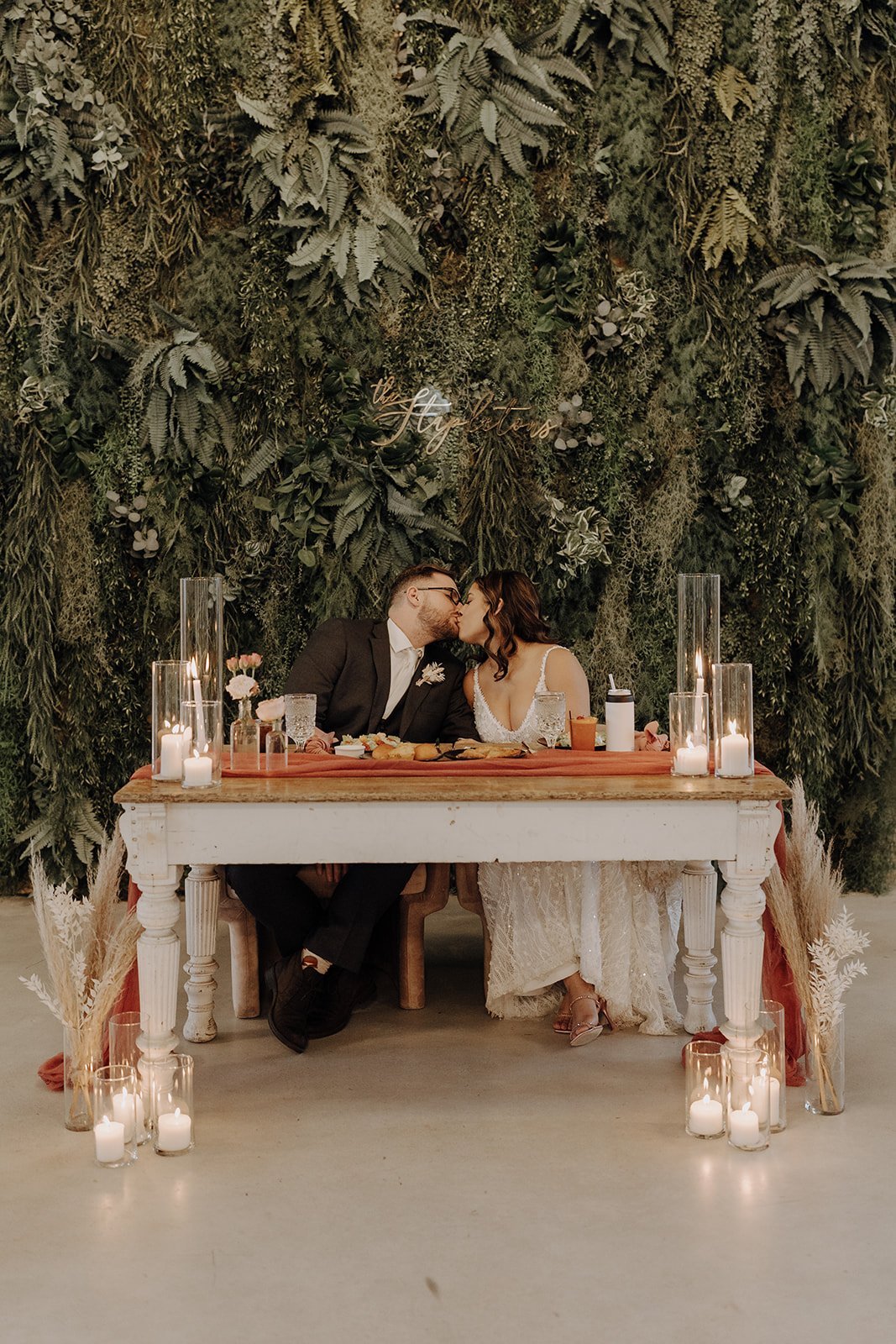 Bride and groom sitting and kissing at the head table at their reception in Austin, Texas