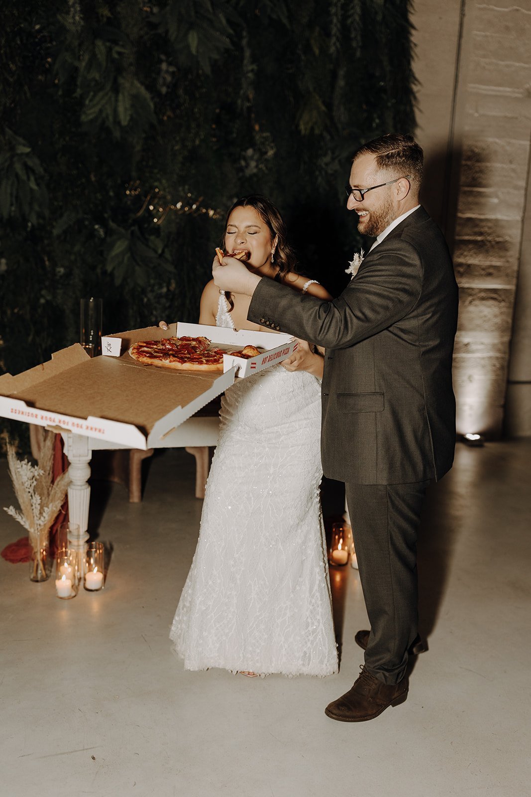 Groom feeding bride pizza during Austin wedding reception