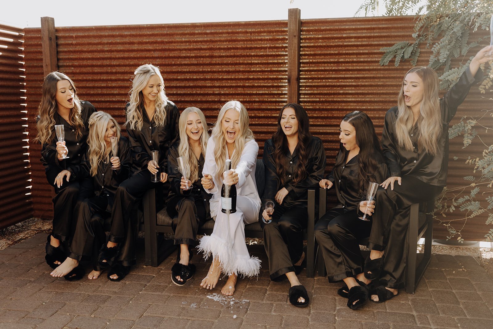 Bride popping champagne with wedding party