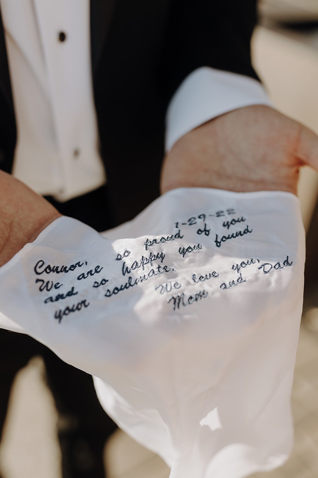 Groom holding personalized handkerchief from his parents