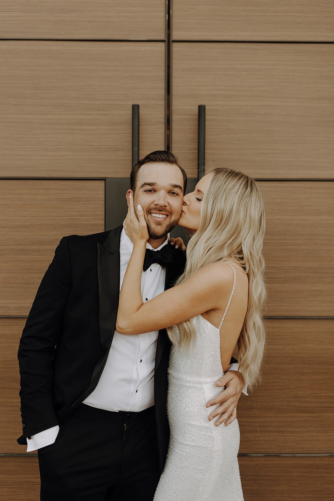 Bride kissing groom on the cheek at desert wedding