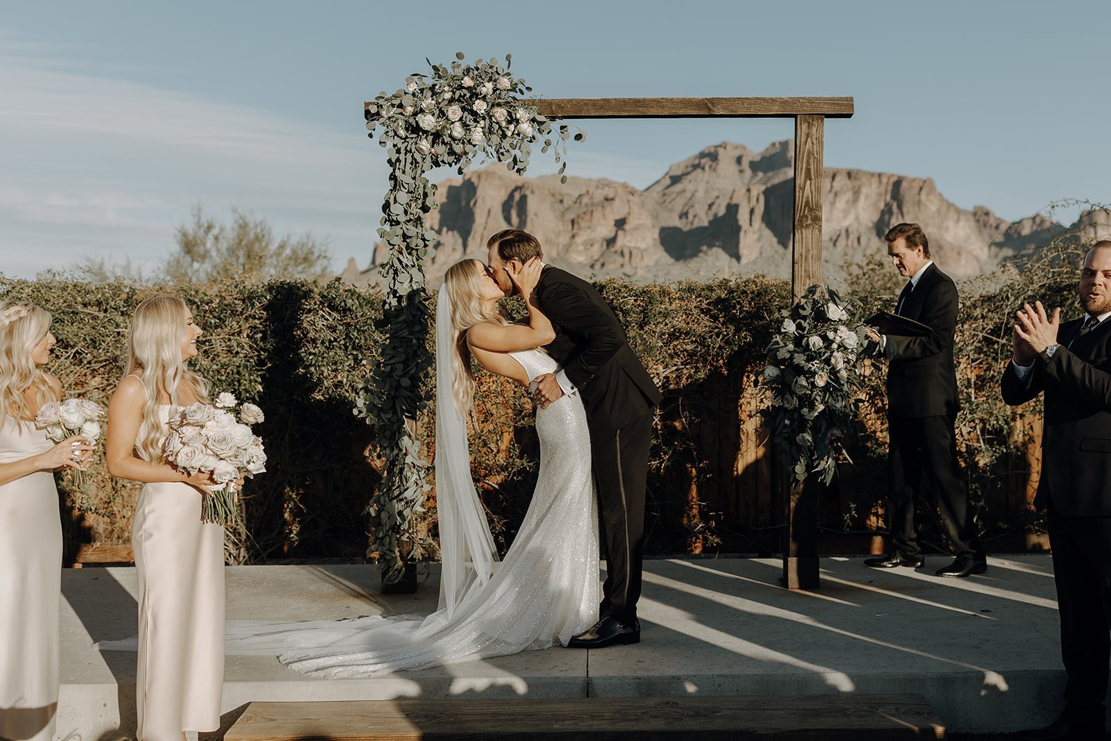 Bride and groom kiss at desert wedding altar