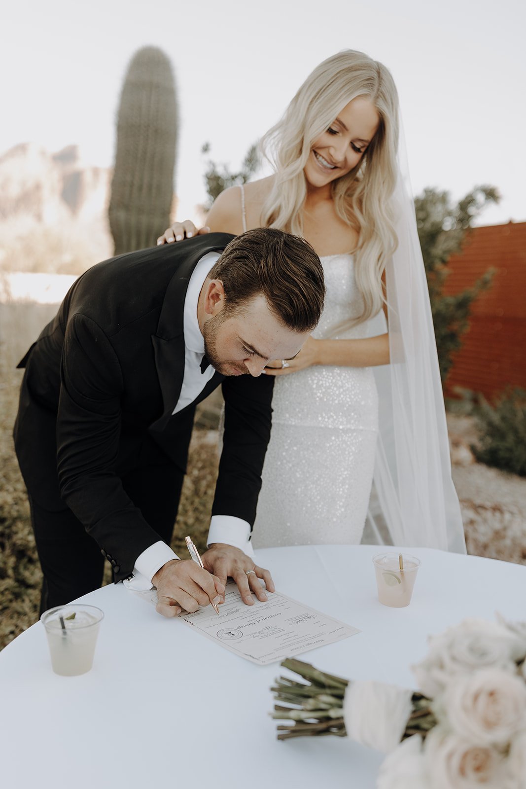 Groom signing marriage license while bride looks over his shoulder