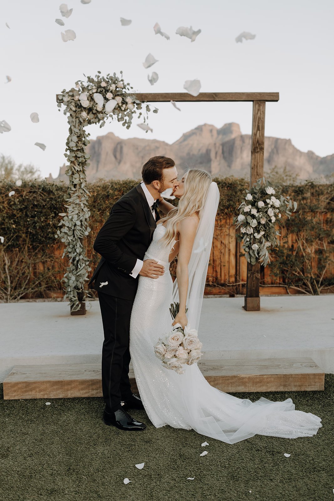 Bride and groom kissing in front of the wedding altar at their desert wedding at The Paseo wedding venue