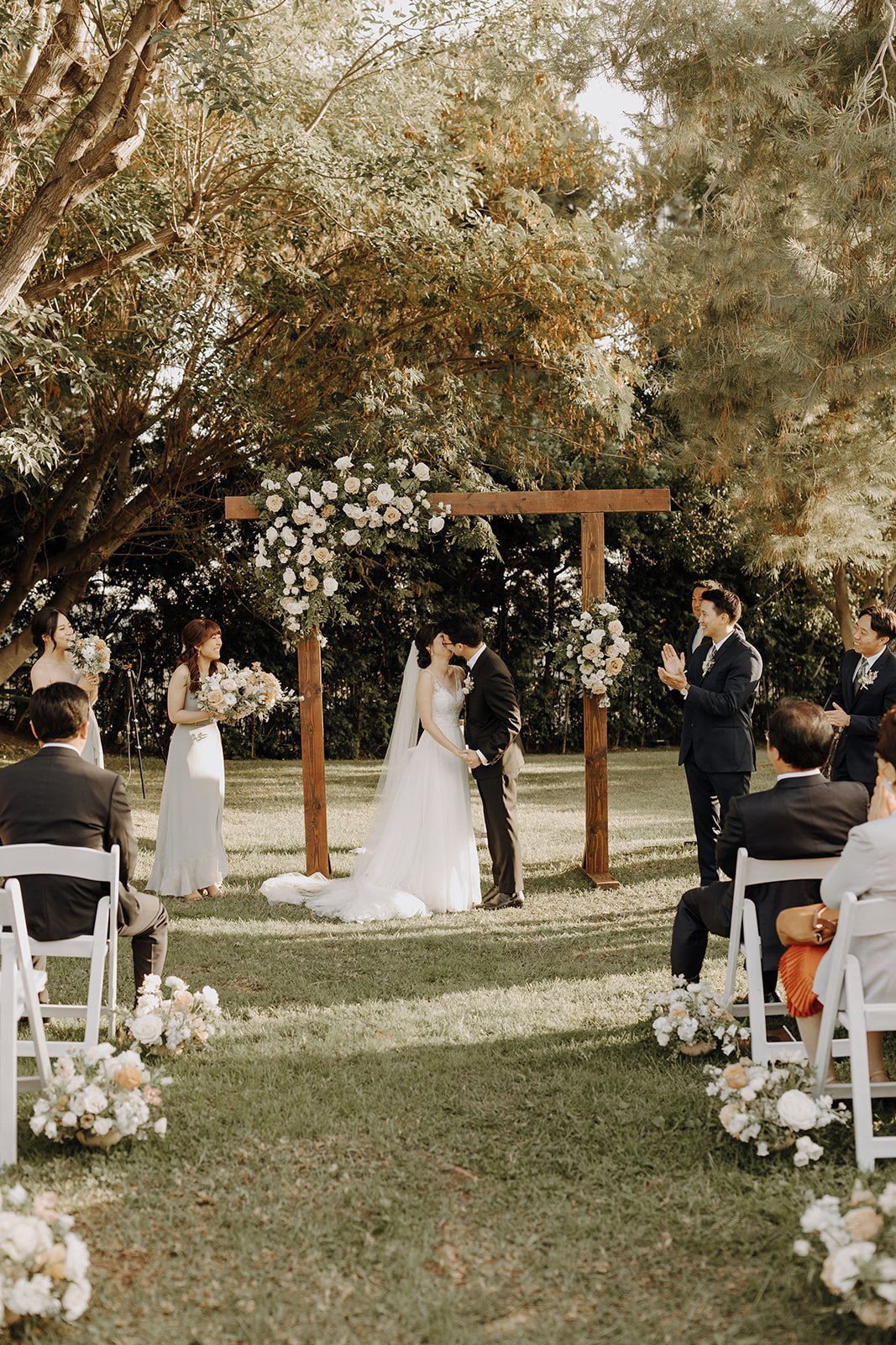 Bride and groom kiss at outdoor wedding altar