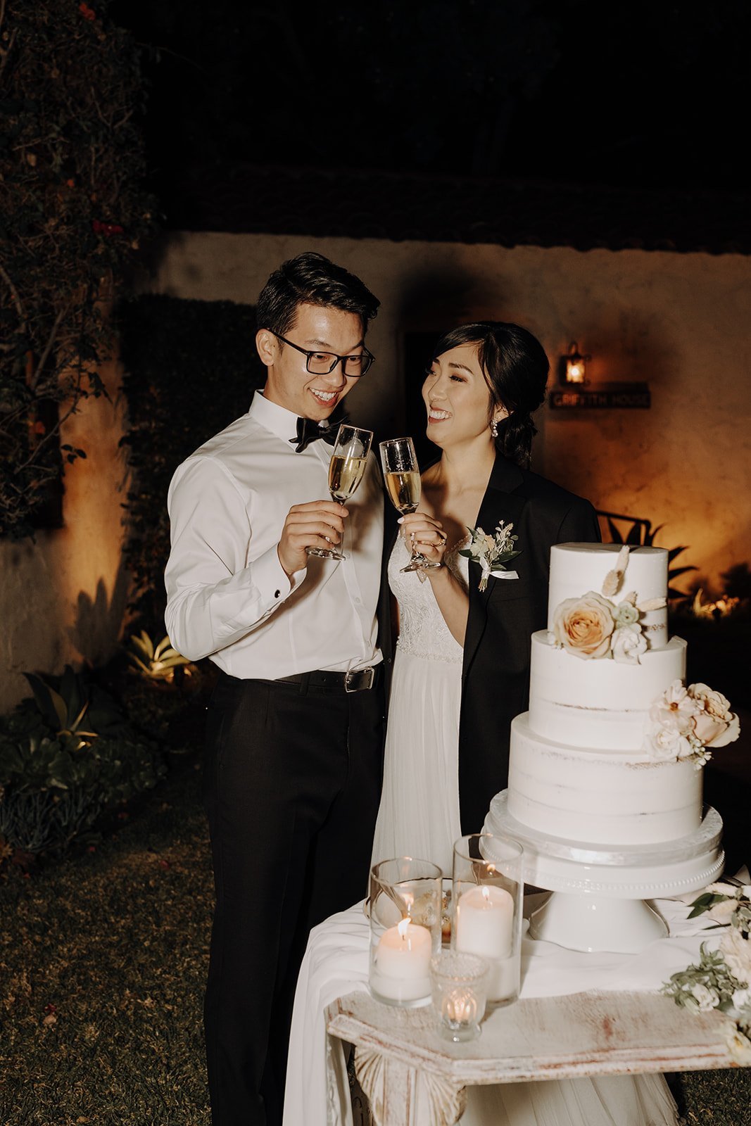 Bride and groom cheers with champagne after cutting wedding cake