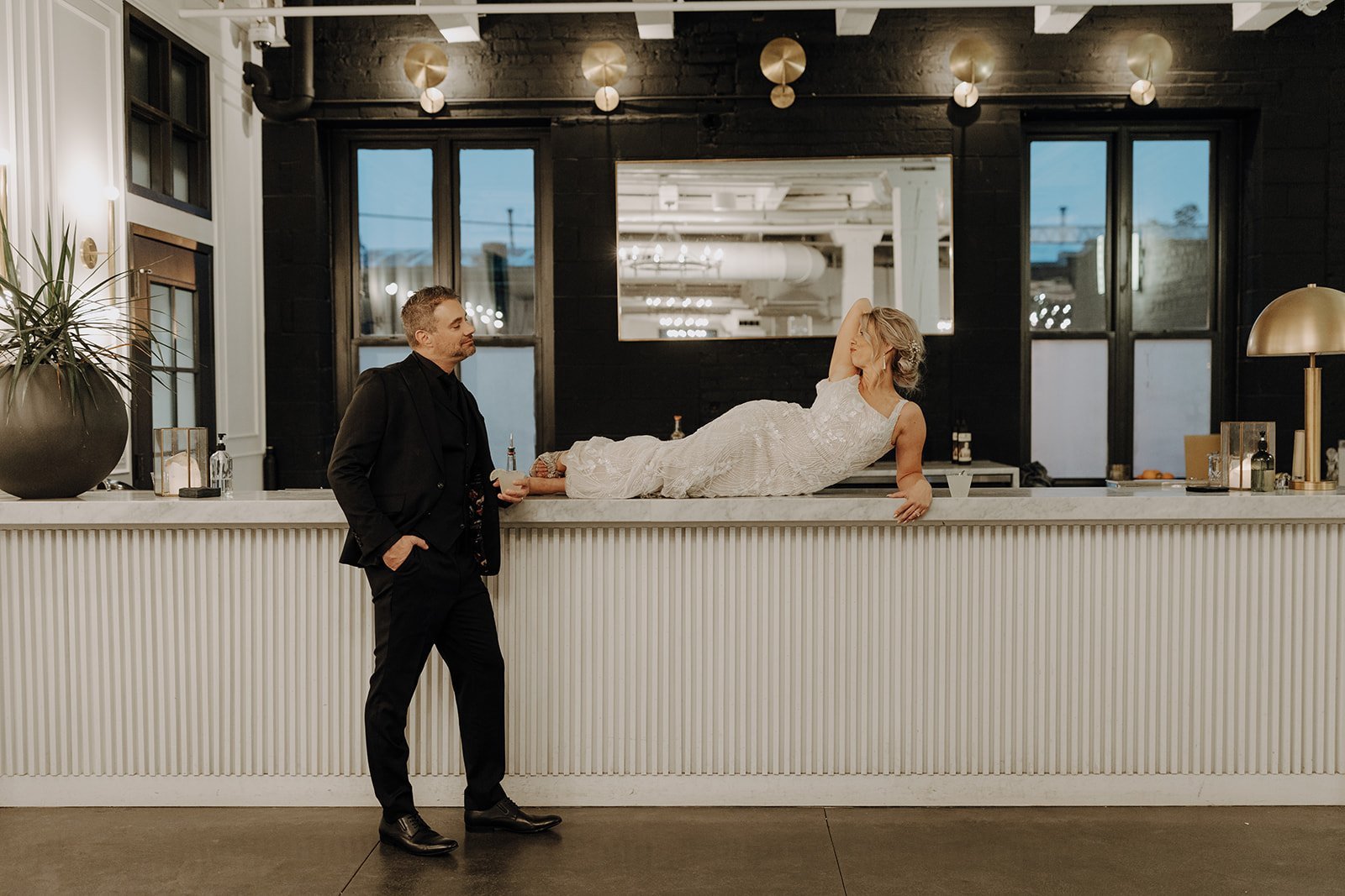 Bride laying on bar top during couple portraits at non-traditional wedding
