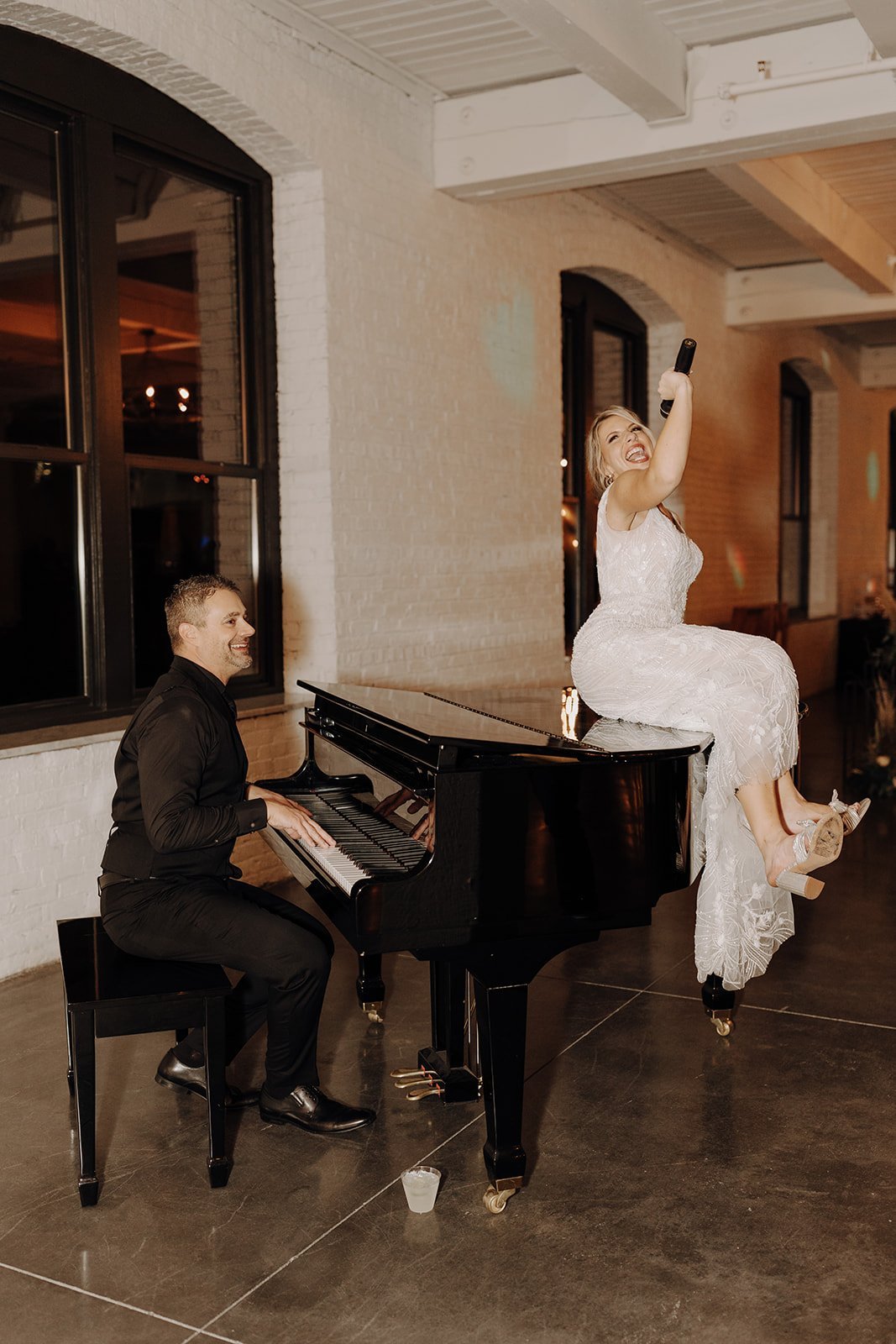 Groom playing piano while bride sings at non-traditional wedding reception