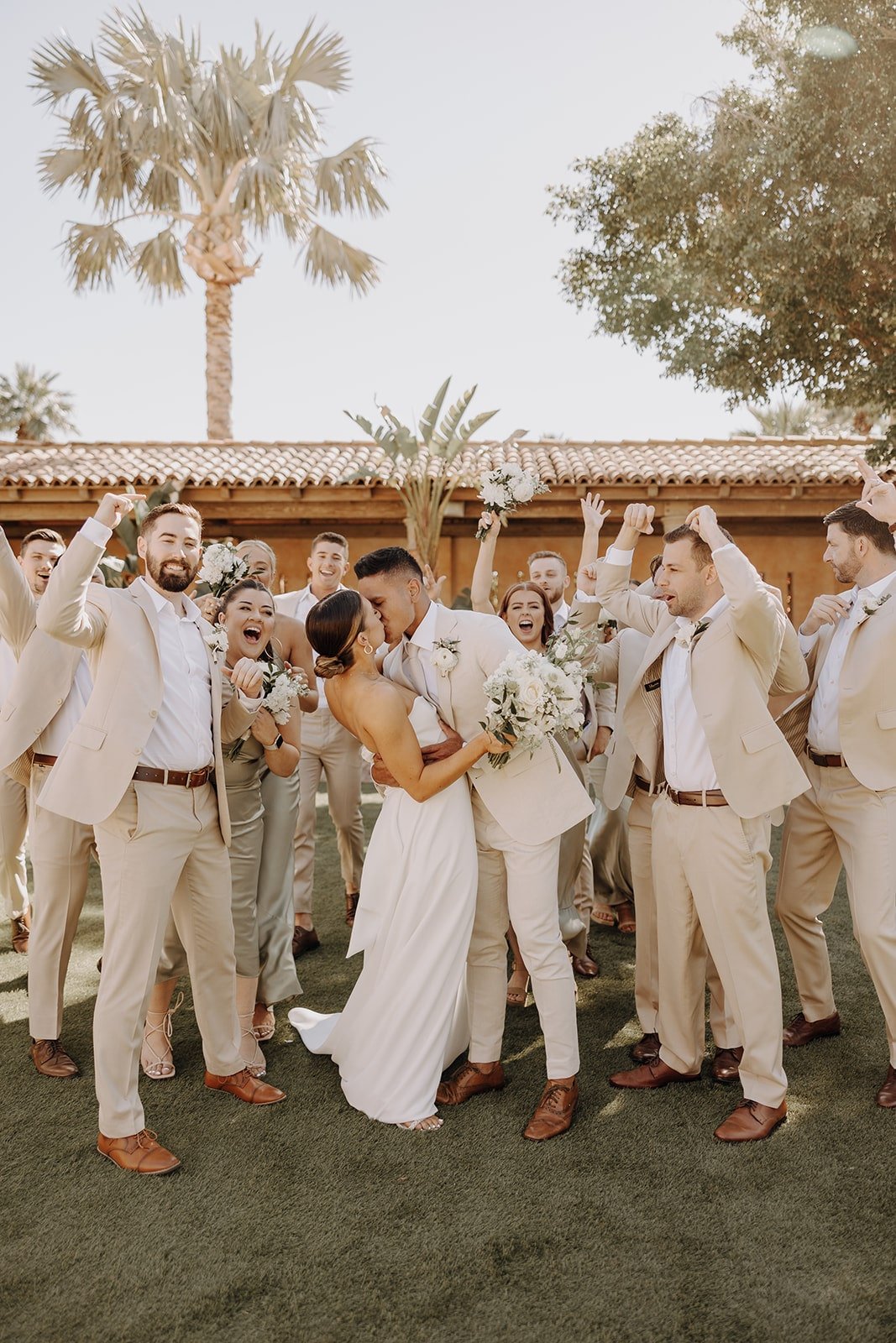 Wedding party cheers while bride and groom kiss for photos at Royal Palms Resort &amp; Spa
