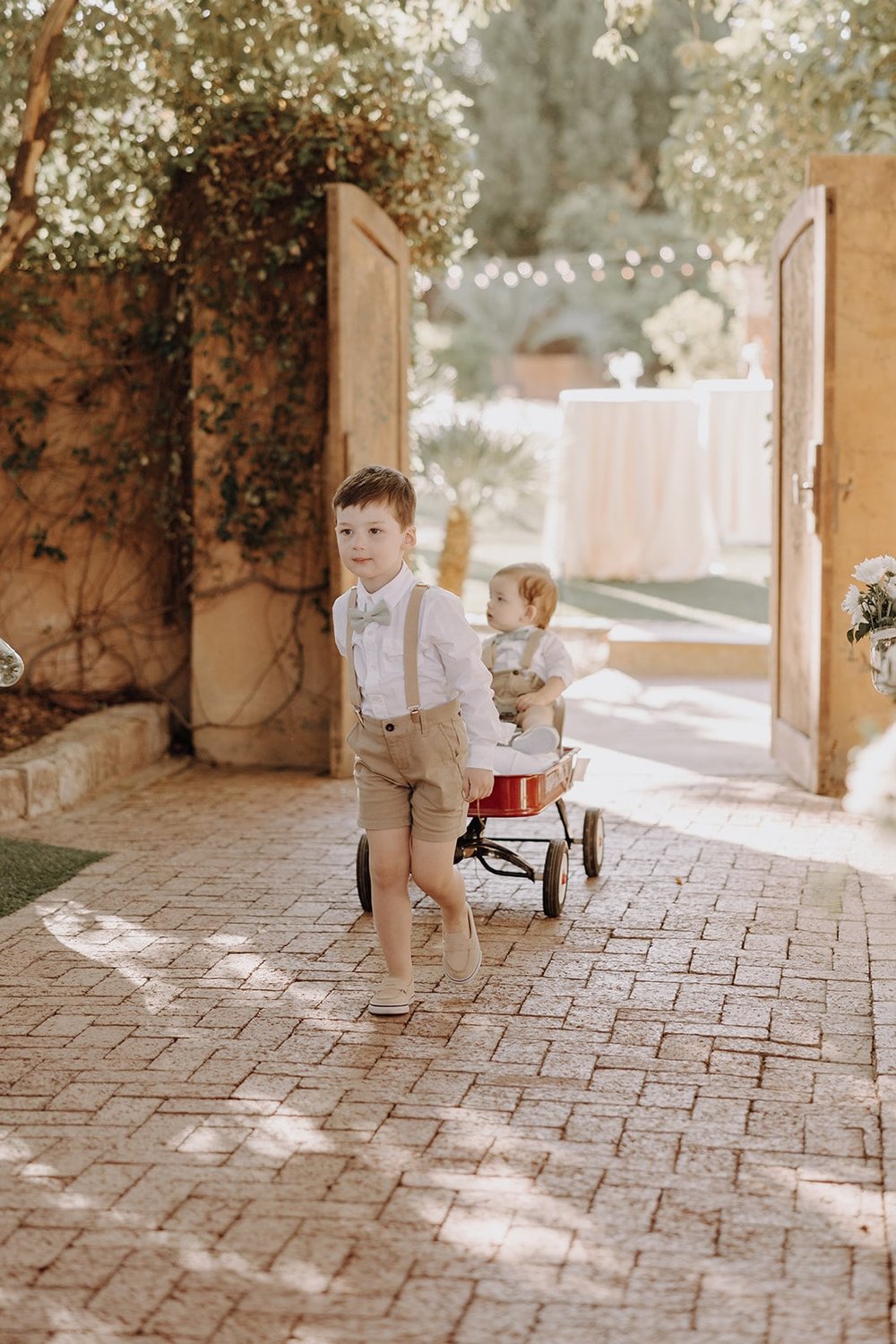 Young boy pulls wagon down the wedding aisle at luxury resort wedding in Arizona