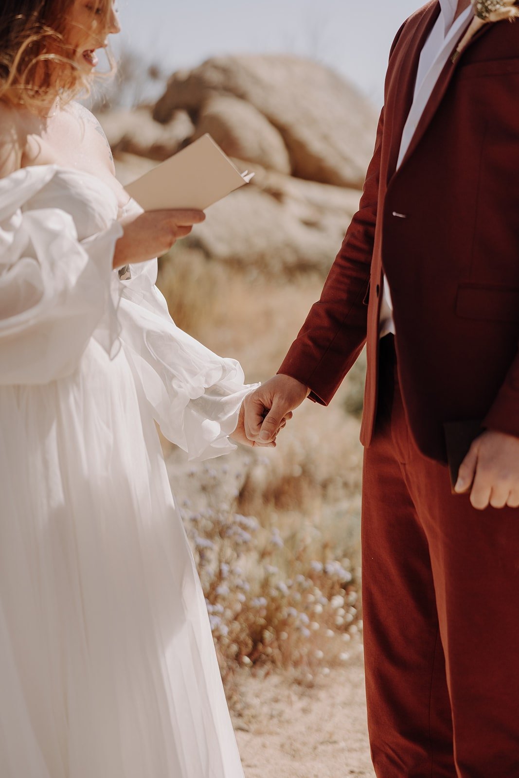 Bride and groom hold hands while exchanging personal vows after wedding first look in Joshua Trua