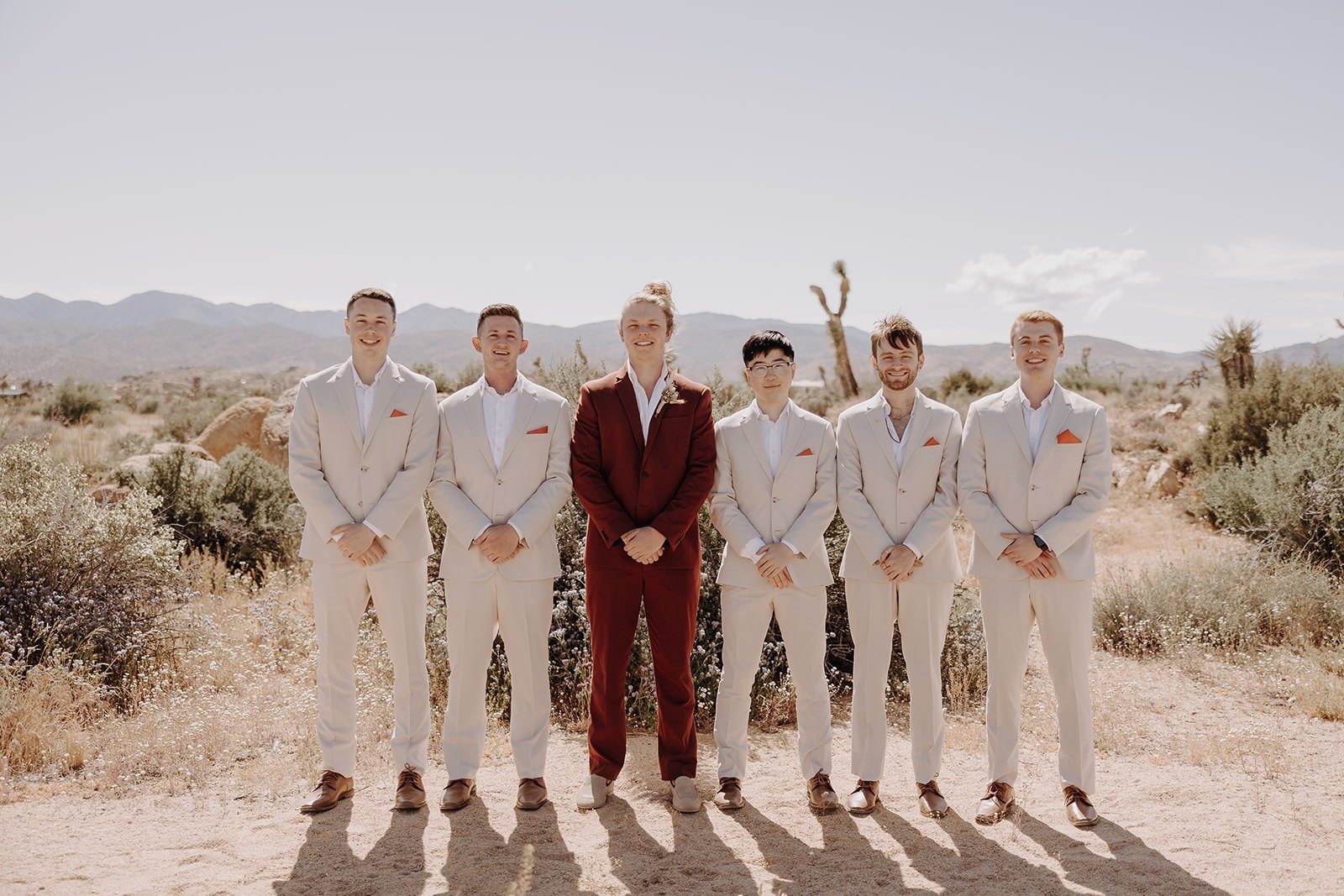 Groom wearing burgundy suit and groomsmen wearing light beige suits for wedding party photos in Joshua Tree