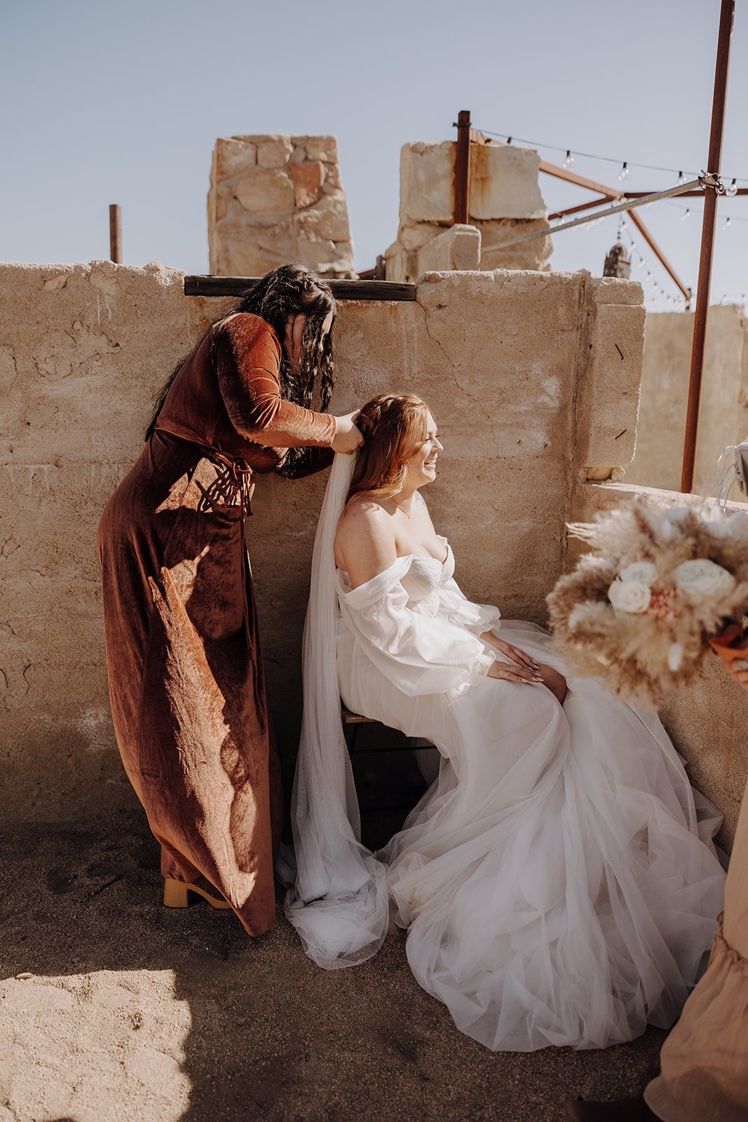 Bridesmaid helping bride with veil before wedding ceremony at The Ruin Venue in Joshua Tree