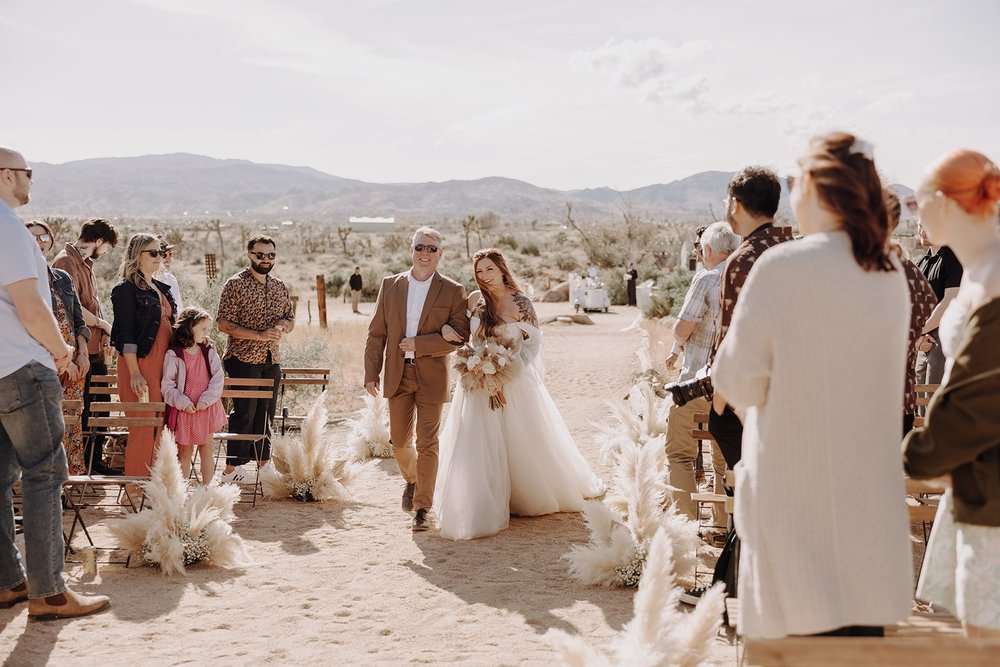 Bride enters outdoor wedding ceremony with father at The Ruin wedding venue in Joshua Tree