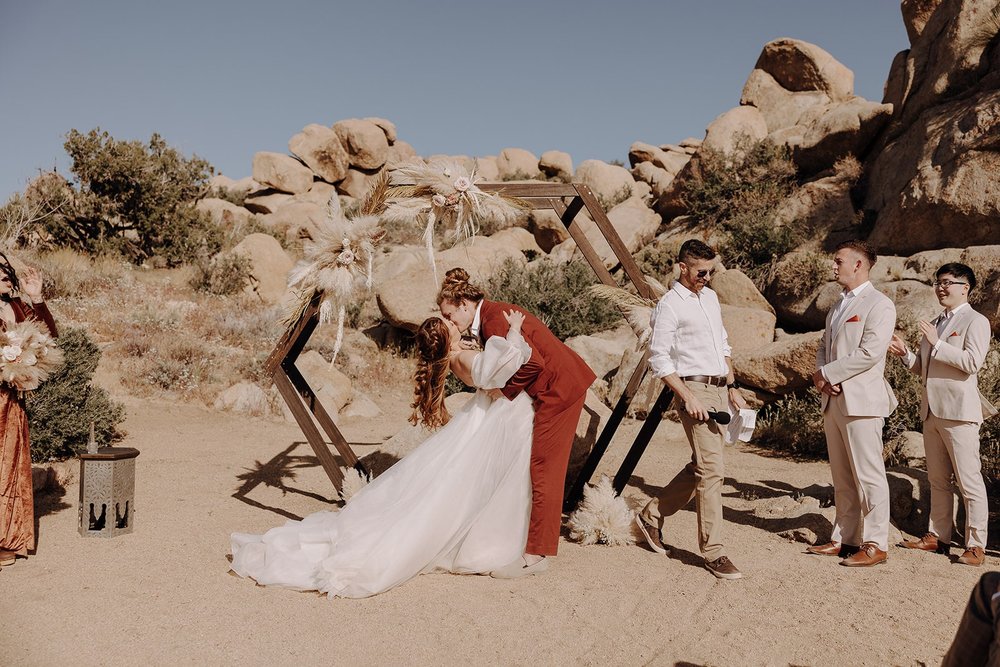 Groom dips bride for a kiss at their Ruin Venue wedding in Joshua Tree