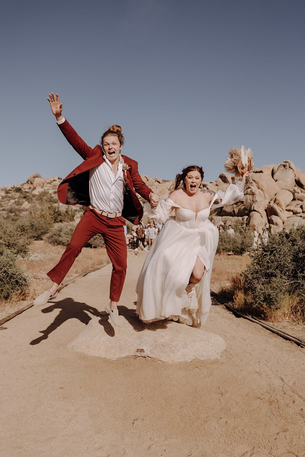 Bride and groom run and jump after their Joshua Tree wedding ceremony