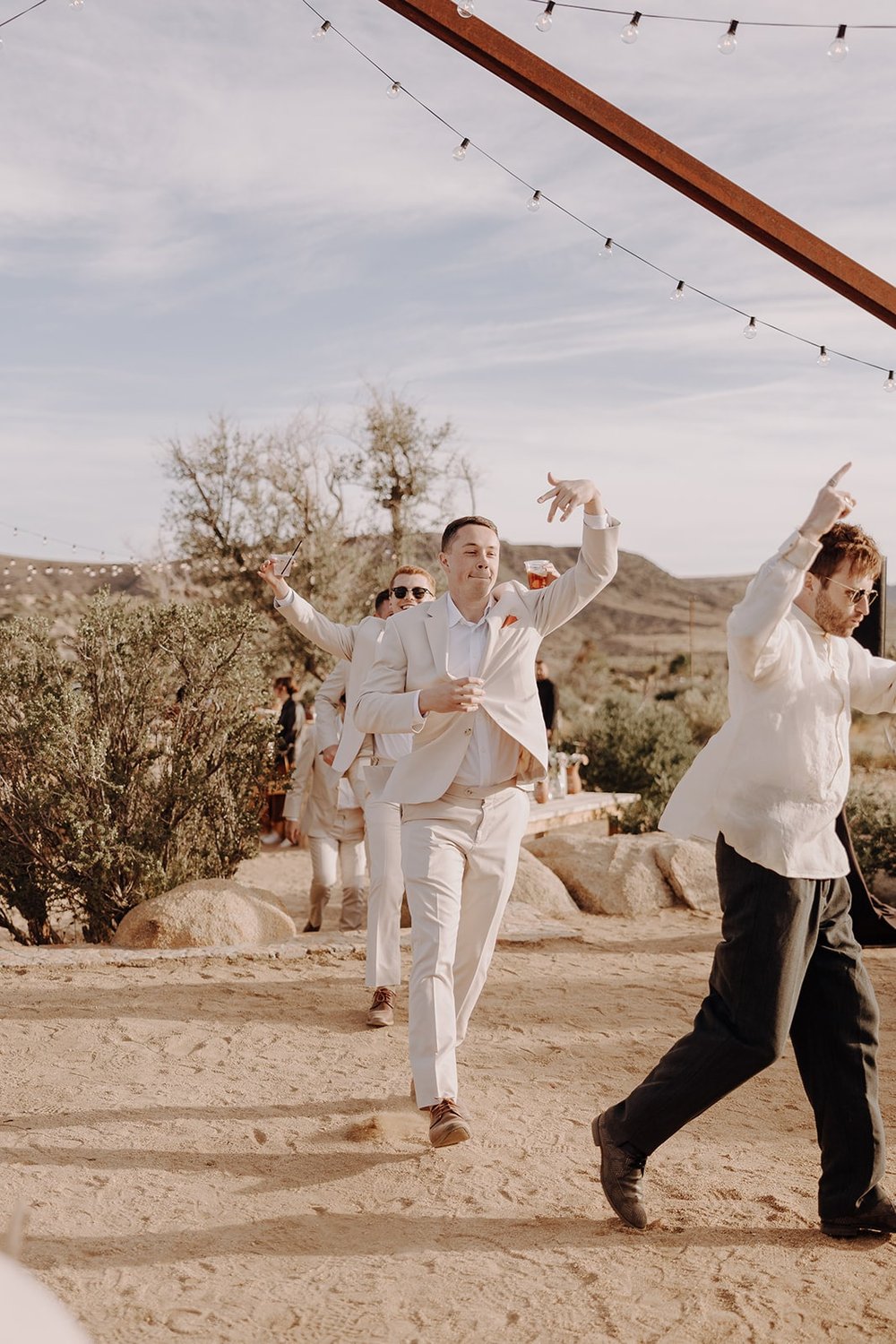 Groomsmen enter the wedding reception with drinks in hand