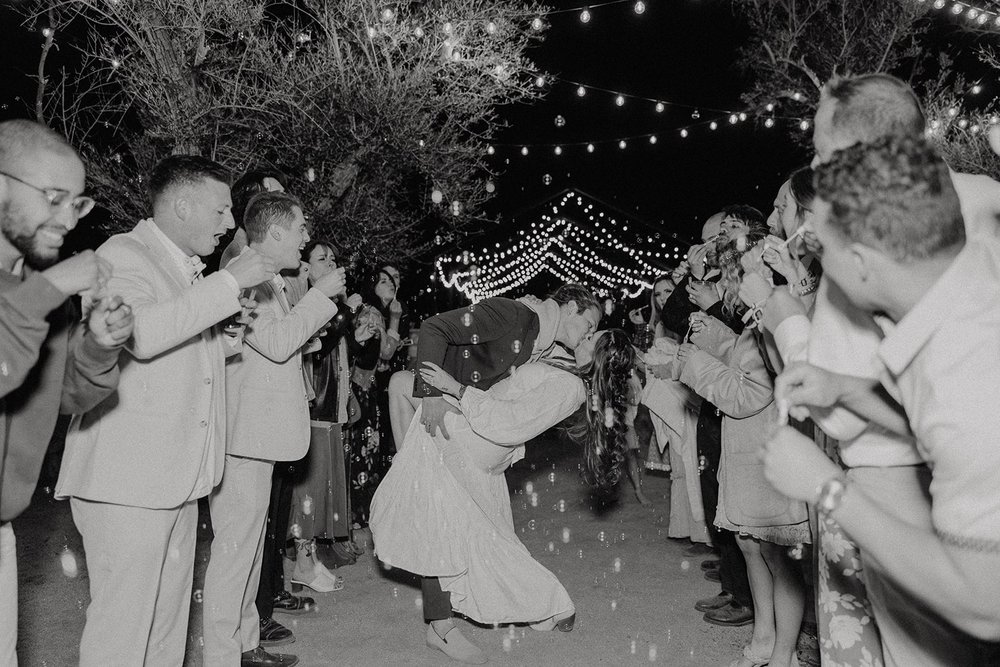 Groom dips bride for a kiss during bubble exit at Joshua Tree wedding