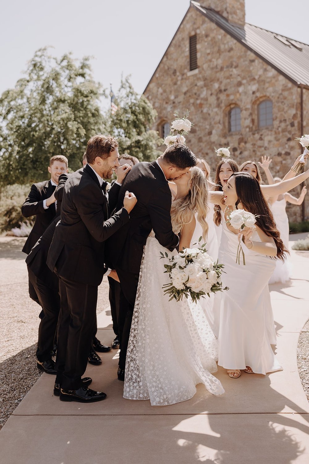 Bride and groom kiss during wedding party photos in California