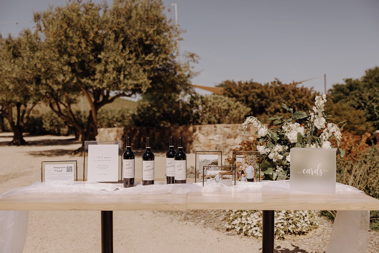 Welcome table with wine and photos at Tuscan-style wedding in California