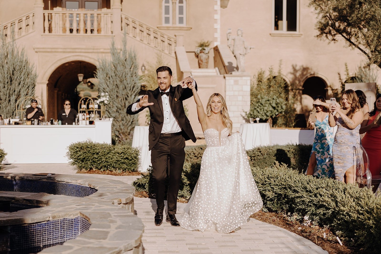 Bride and groom cheer while entering their luxury wedding reception at Allegretto Vineyard Resort