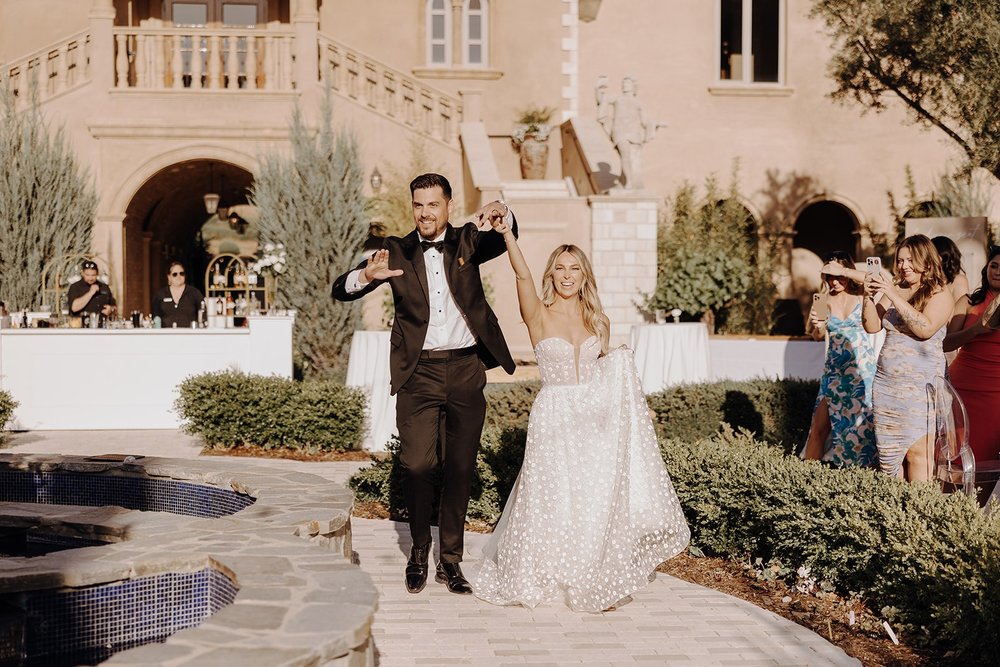 Bride and groom cheer while entering their luxury wedding reception at Allegretto Vineyard Resort
