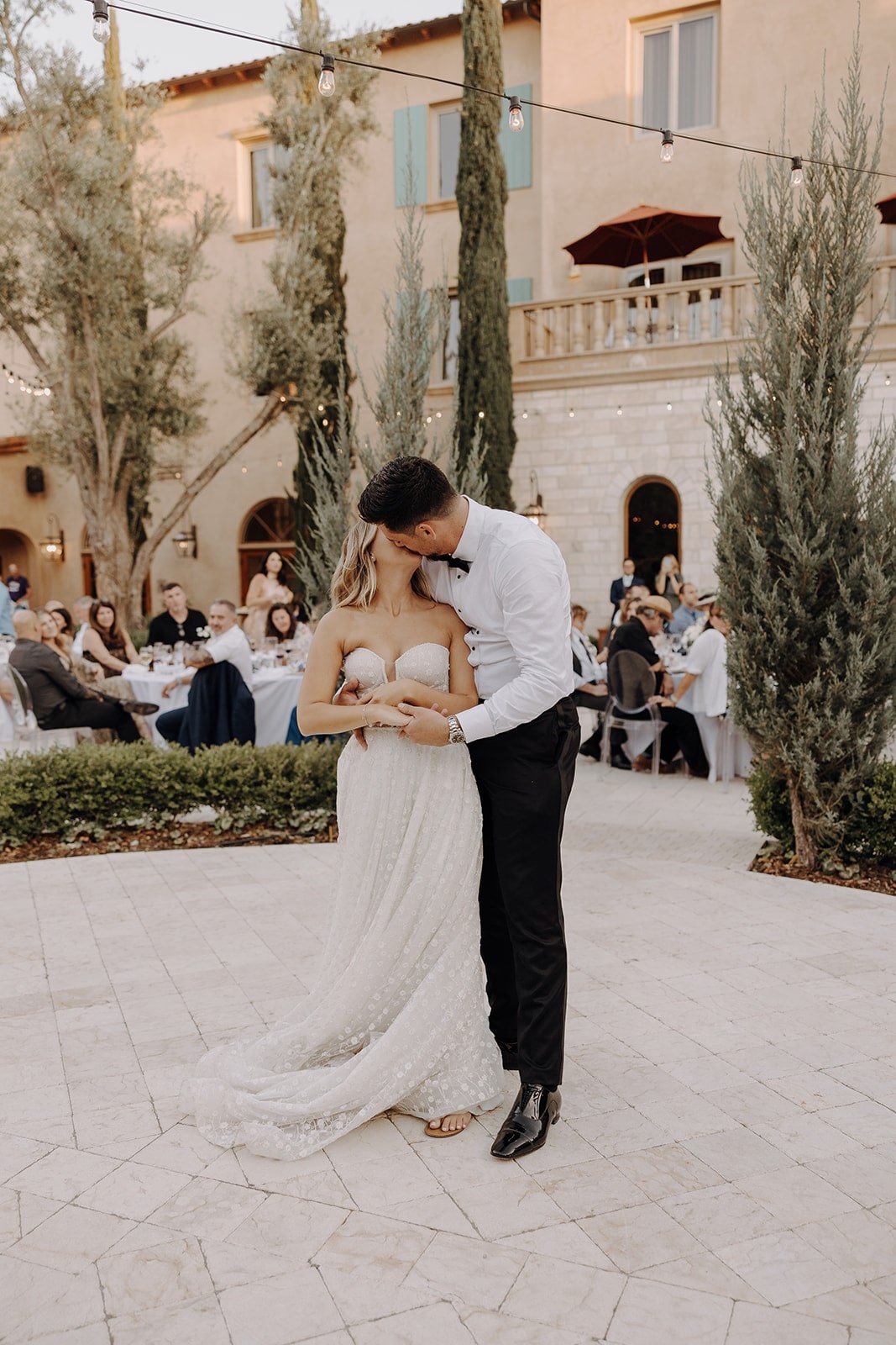 Bride and groom kiss after first dance at outdoor wedding reception