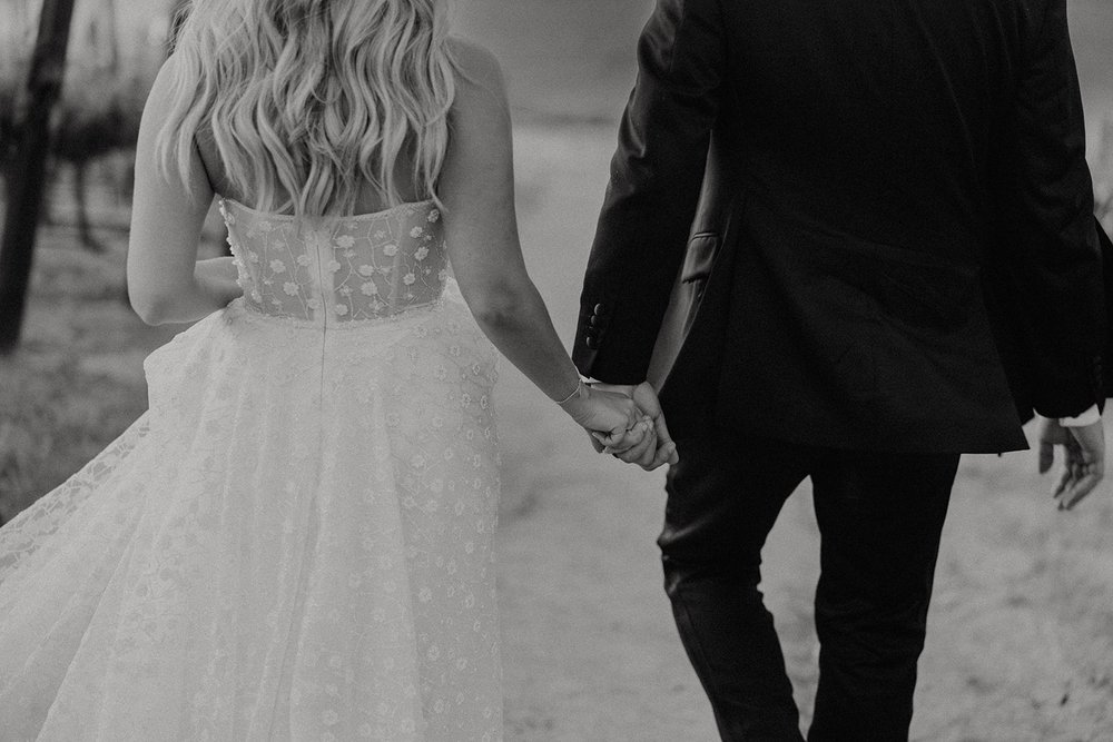 Bride and groom hold hands during sunset wedding portraits at luxury wedding venue in California