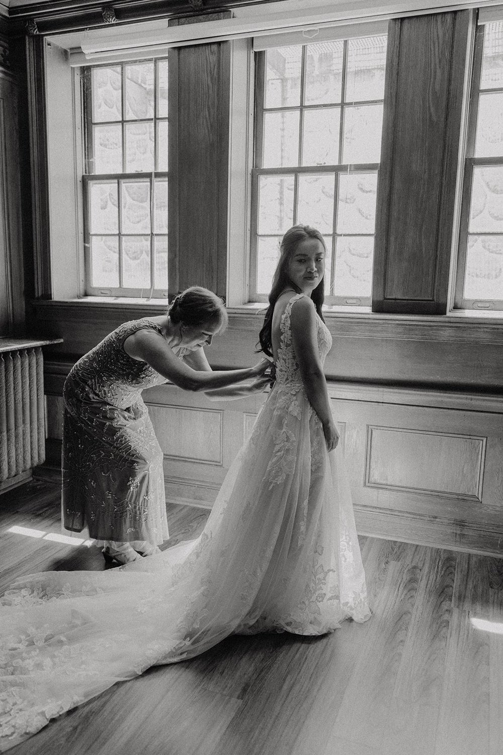 Bride getting zipped into her white wedding dress at Lairmont Manor