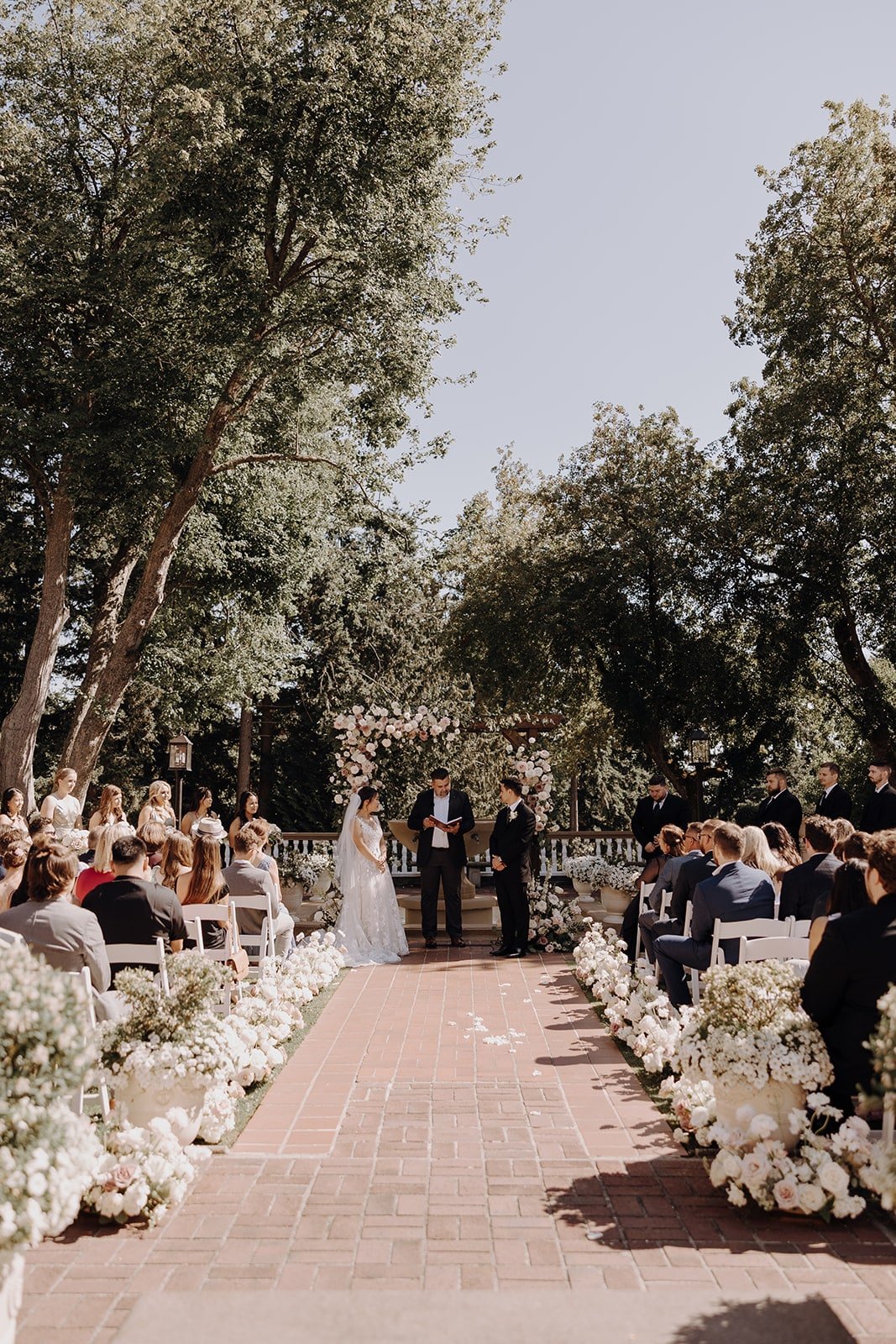 Bride and groom stand under a floral arch at their outdoor Washington wedding