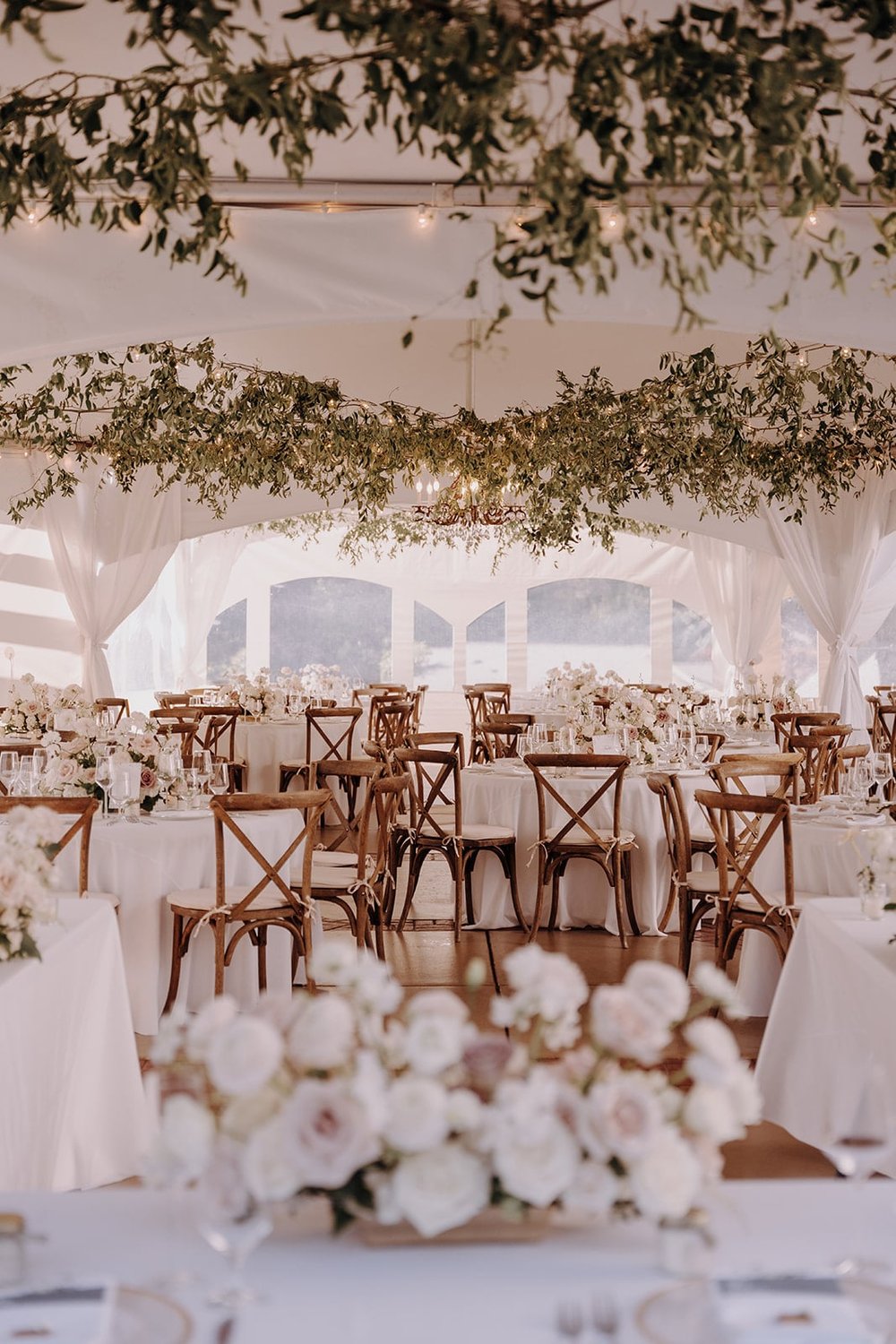 White reception tables with wood chairs and white cushions at Lairmont Manor wedding