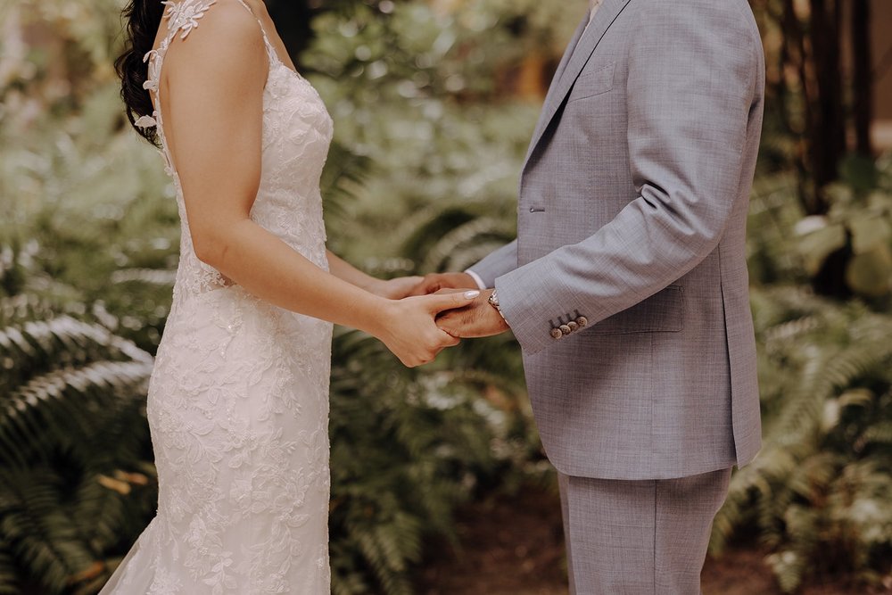 Bride and groom hold hands during wedding first look at tropical destination wedding